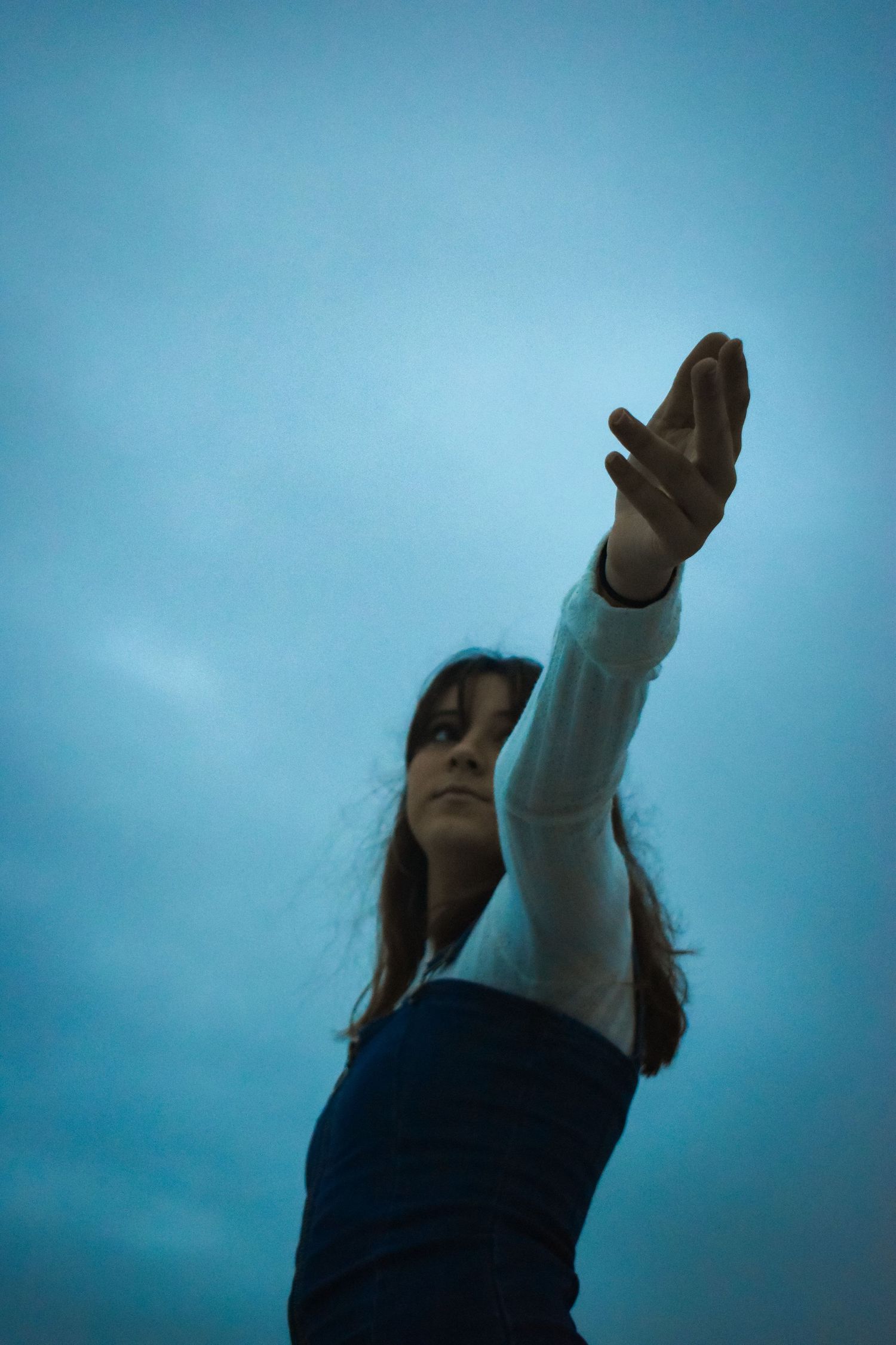A sequence of images showing a person reaching upward against a blue sky background in a fluid motion.