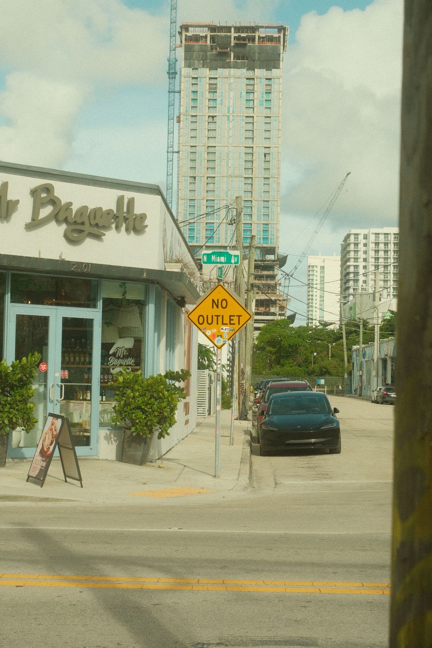 Urban street corner with tall buildings, street signs, and a Biscayne business storefront in Miami's downtown area.