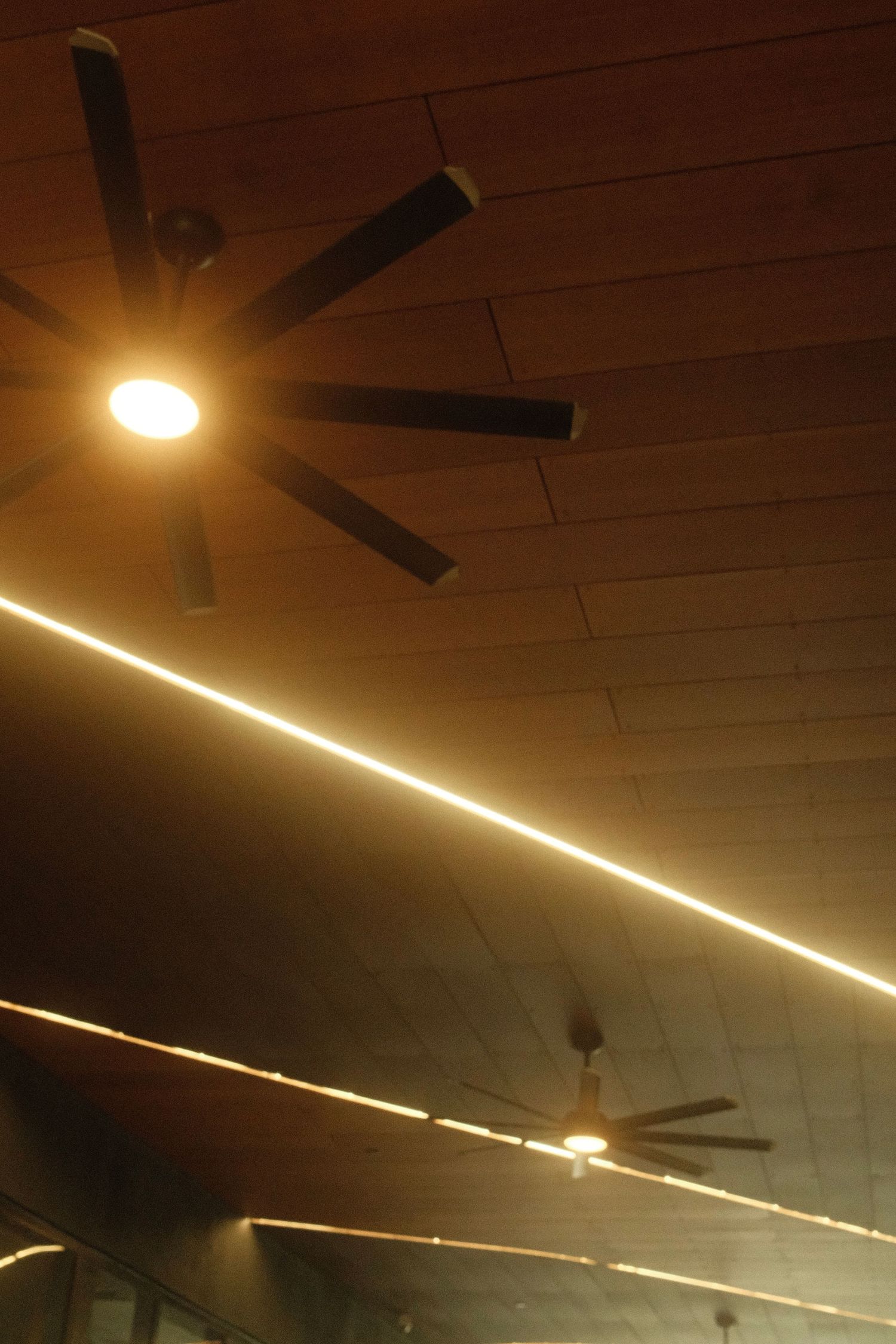 Fluorescent lighting strips create geometric patterns on a dark ceiling in a sequence of photos.