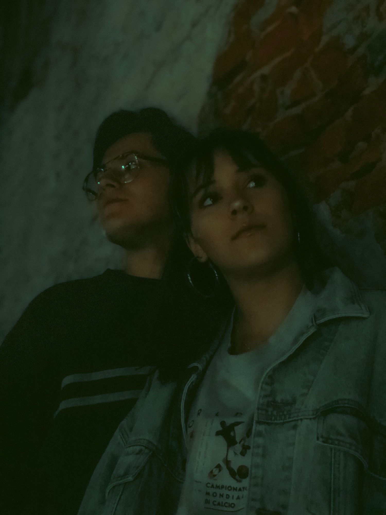 A series of dark, moody portraits showing someone wearing glasses and denim jacket against a shadowy background.
