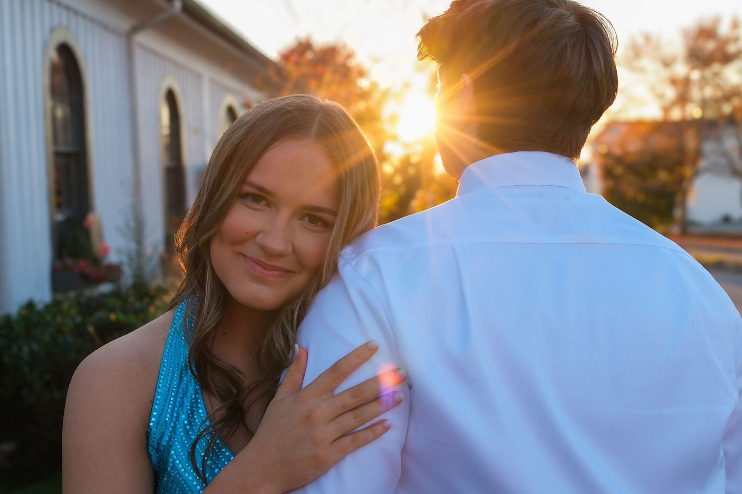 A romantic sunset photoshoot featuring a couple in turquoise and white attire against a warm glowing backdrop.