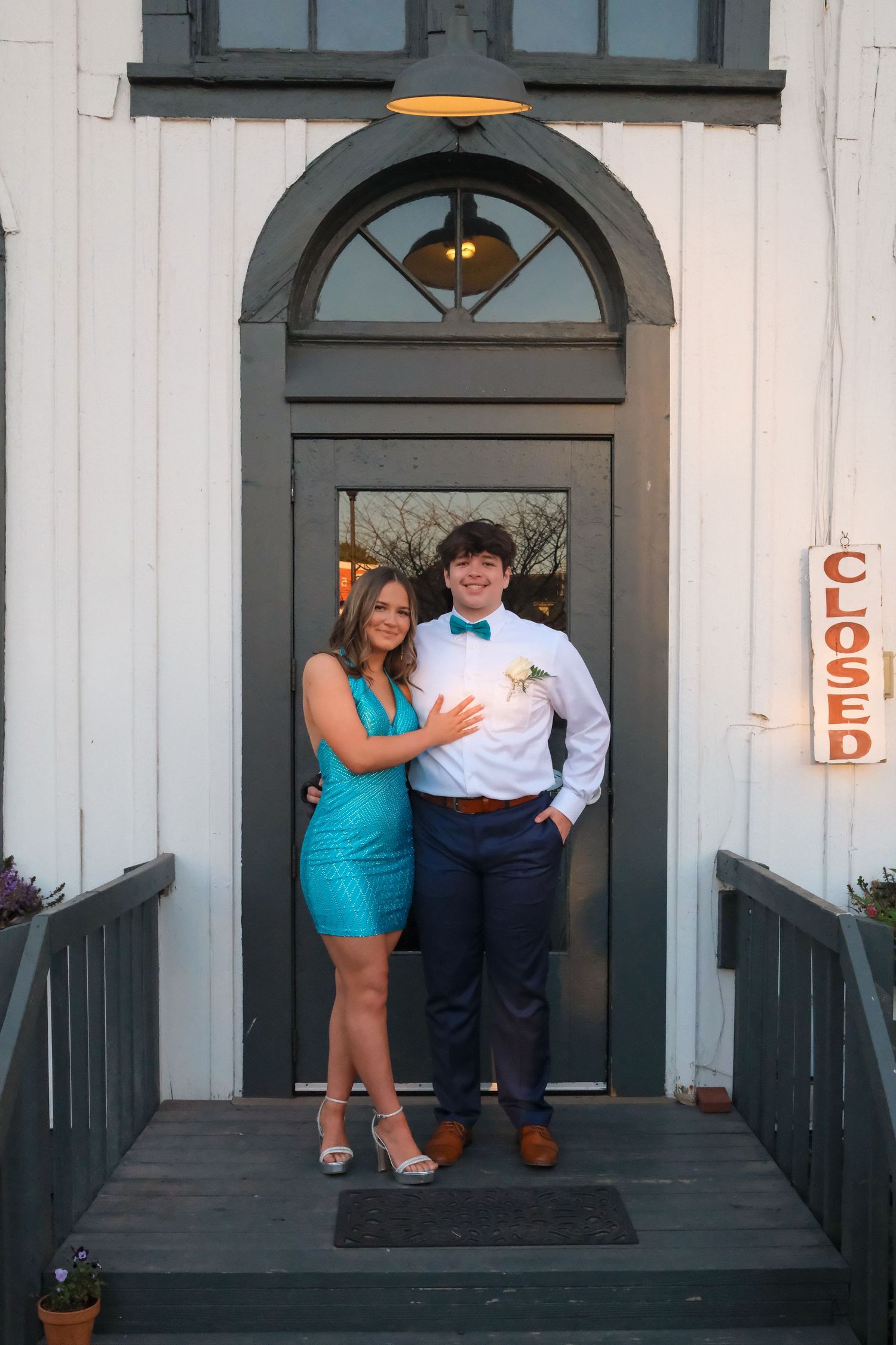 A couple poses in front of white building with arched doorways and green trim during a romantic photoshoot.