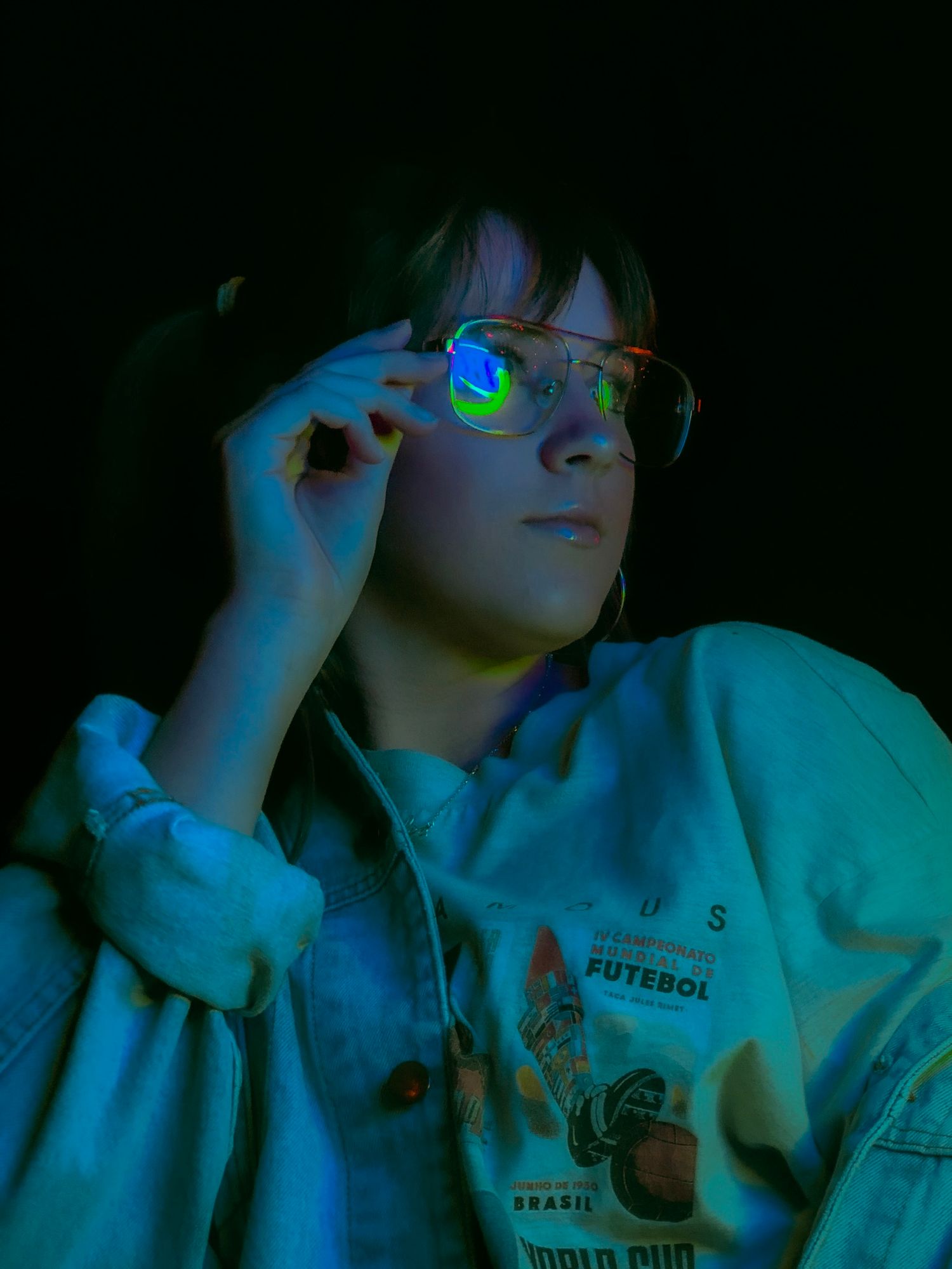 Artistic portrait series in dark lighting with blue neon glow showing someone in white clothing against black background.