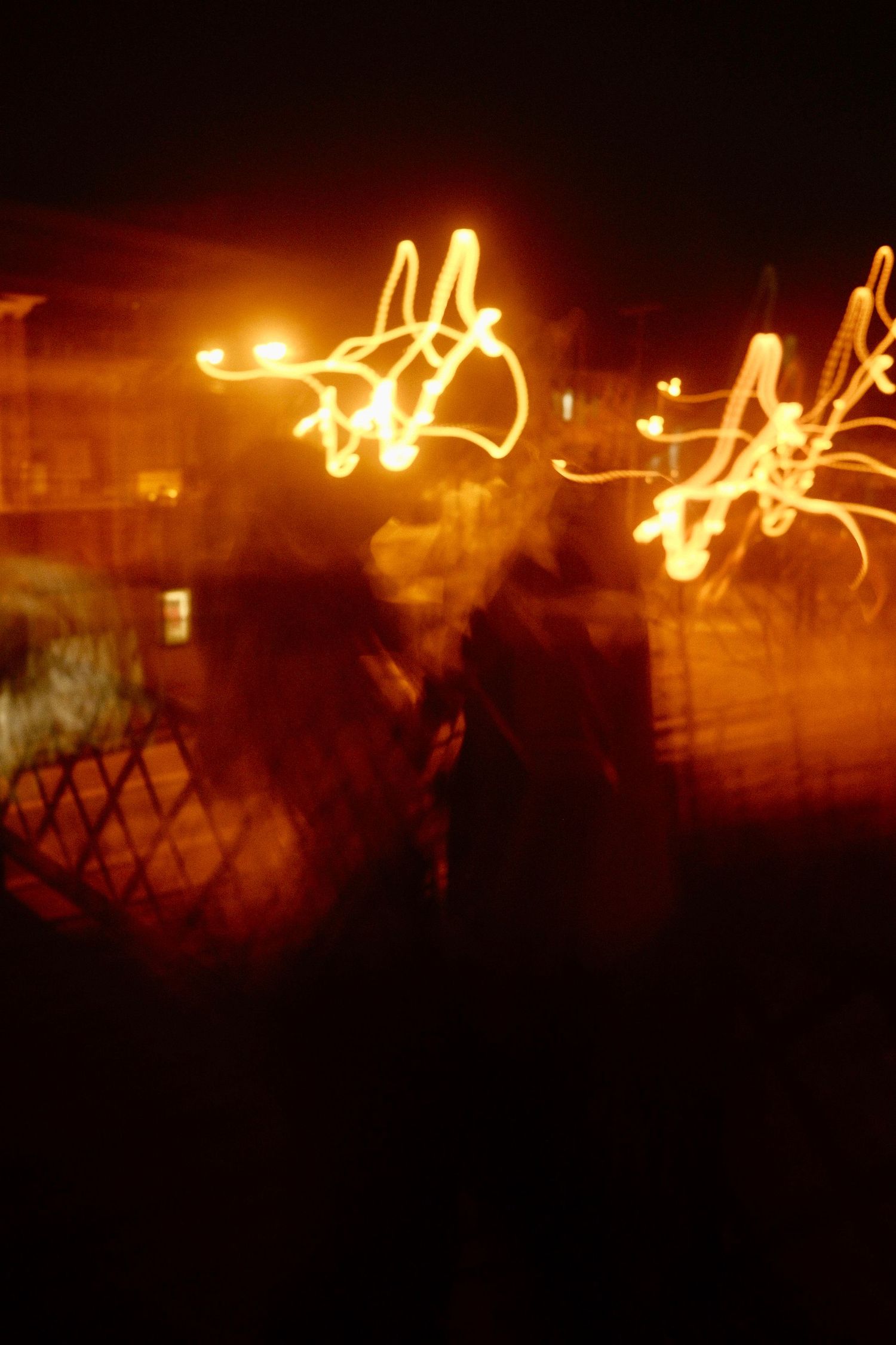 Abstract light trails create glowing patterns against a dark background in a long exposure night photograph.