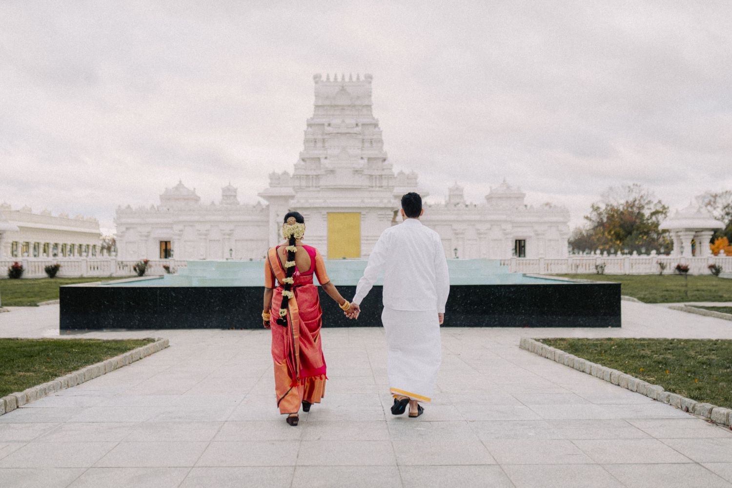 Wide panoramic view of a white temple complex with people visible in the distance.