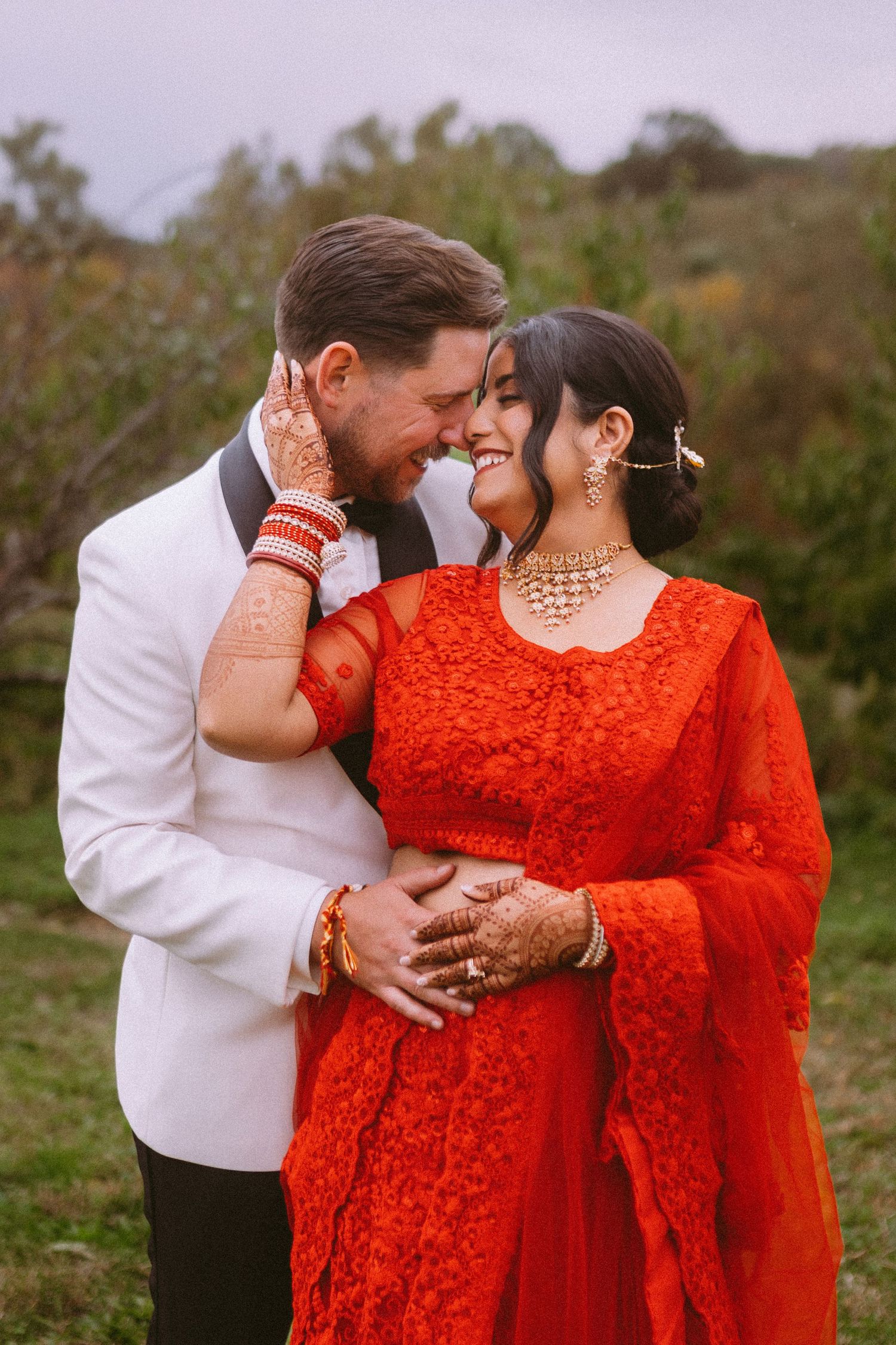 Romantic couple portraits featuring a red lace dress against a natural outdoor setting.