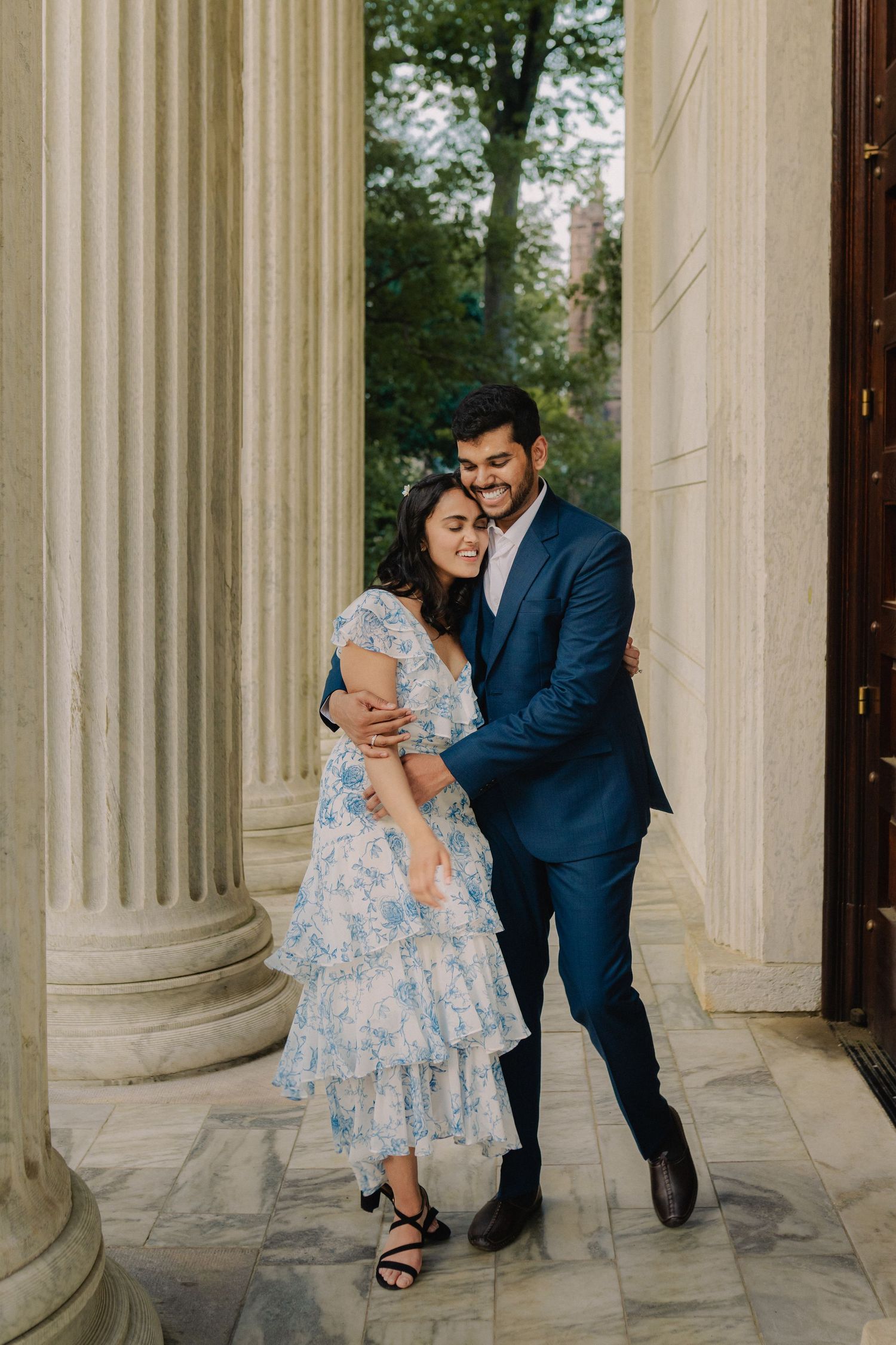 A couple poses playfully between white marble columns in a romantic photoshoot sequence.