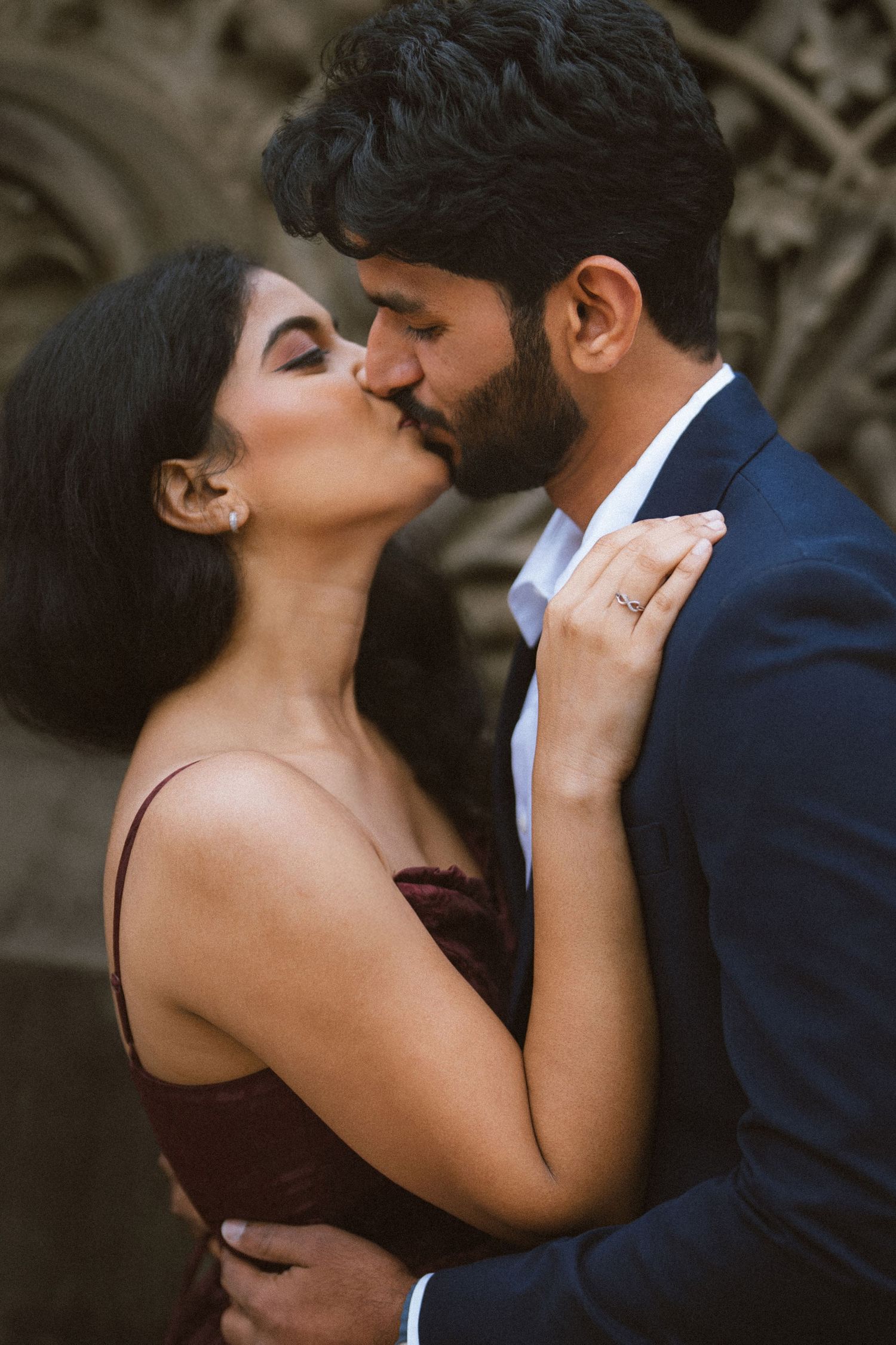 Intimate romantic moment captured against stone architecture background.
