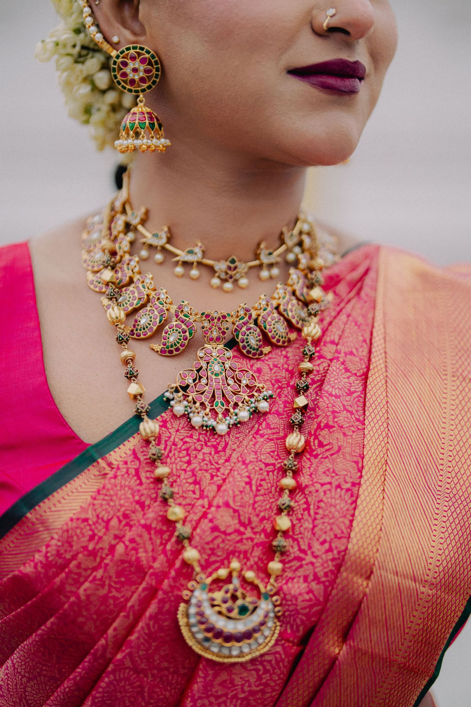 Detailed view of traditional South Indian gold jewelry and pink silk saree.