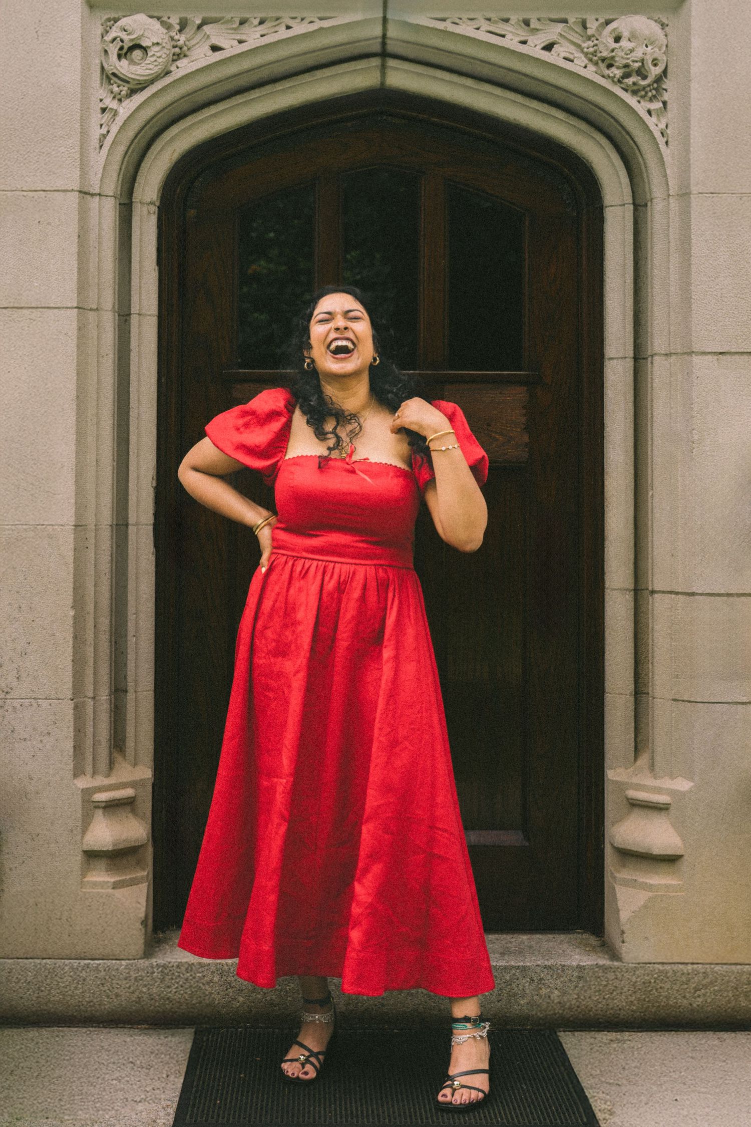 A vibrant red babydoll dress is showcased against an ornate stone archway backdrop in a fashion photoshoot.