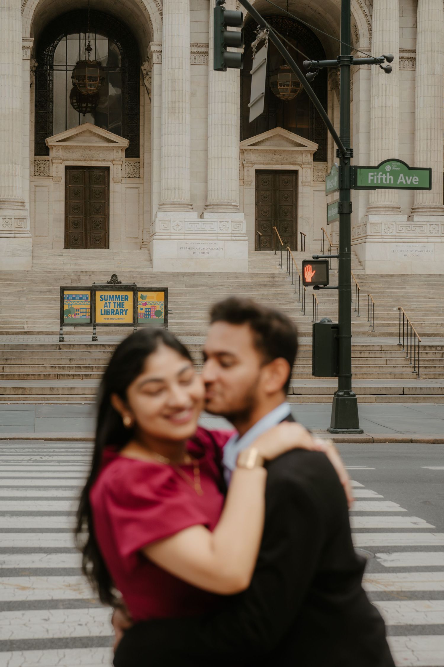 A couple shares a romantic kiss in front of the New York Public Library on Fifth Avenue.