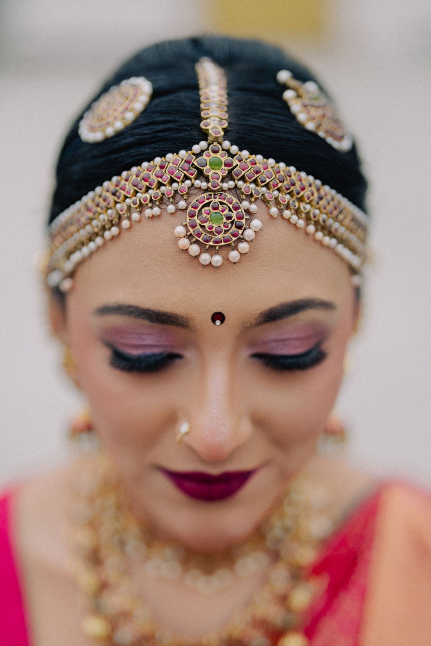 Detailed shots of traditional Indian bridal makeup with jeweled headpiece and burgundy lipstick.