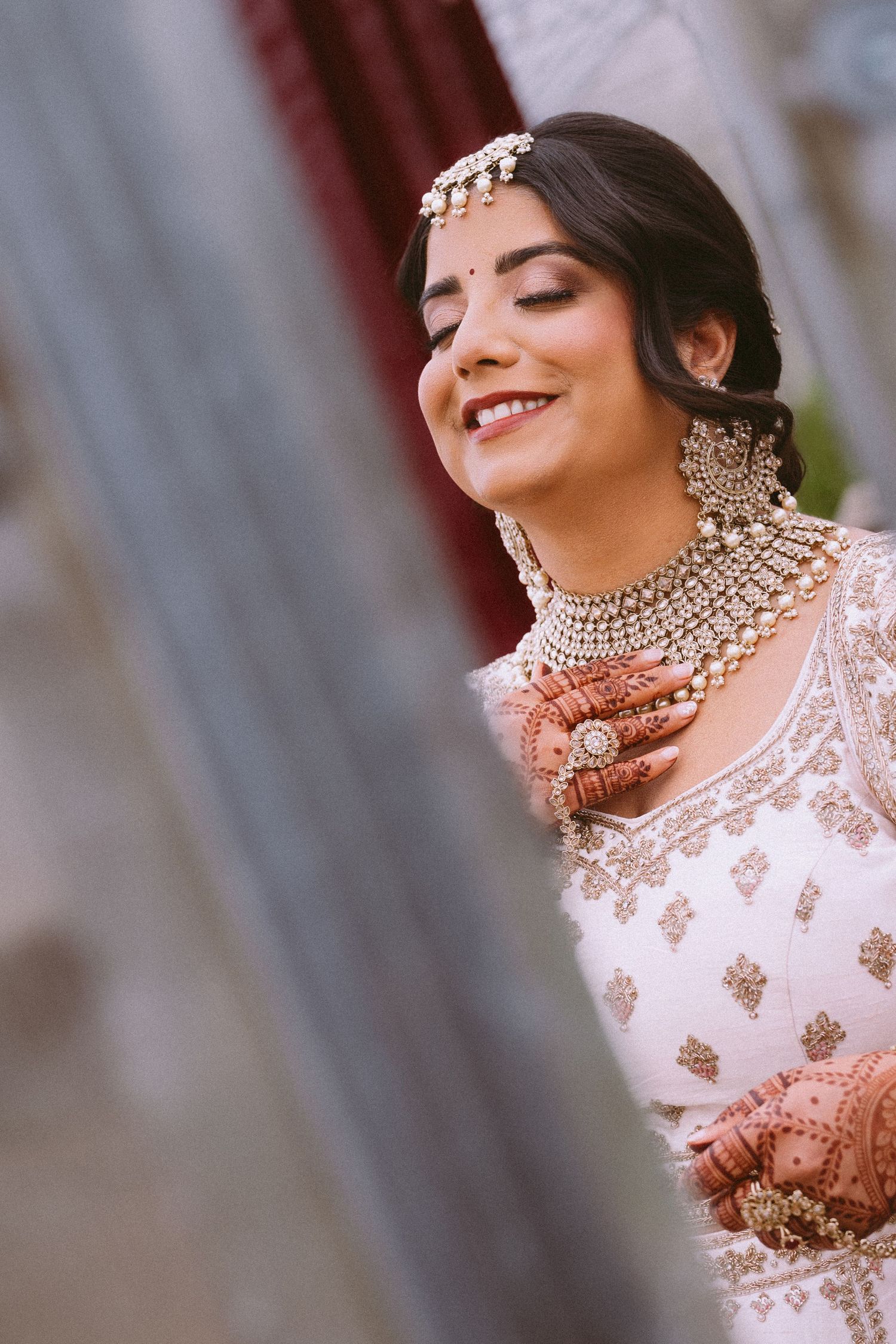 Close-up details of ornate Indian bridal jewelry and white embroidered clothing with intricate designs.