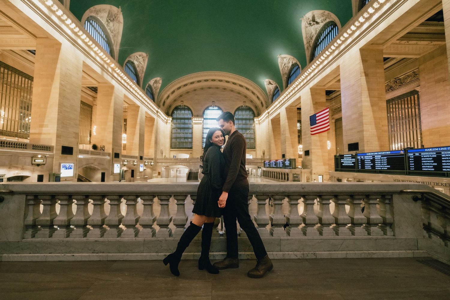 Elegant couple walking together on marble staircase inside Grand Central Terminal's historic main concourse in New York City.