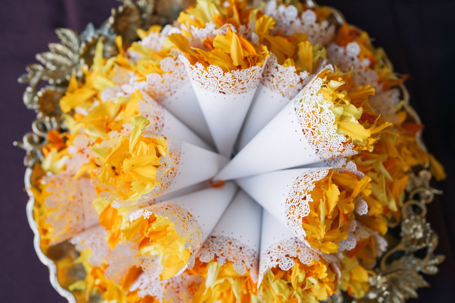 White paper cones filled with yellow flower petals arranged in a circular pattern.