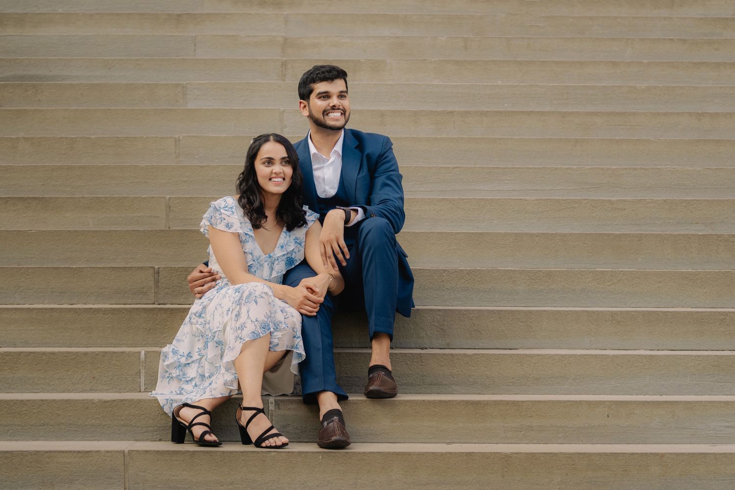 A couple sits together on outdoor stone steps in a casual, romantic moment.