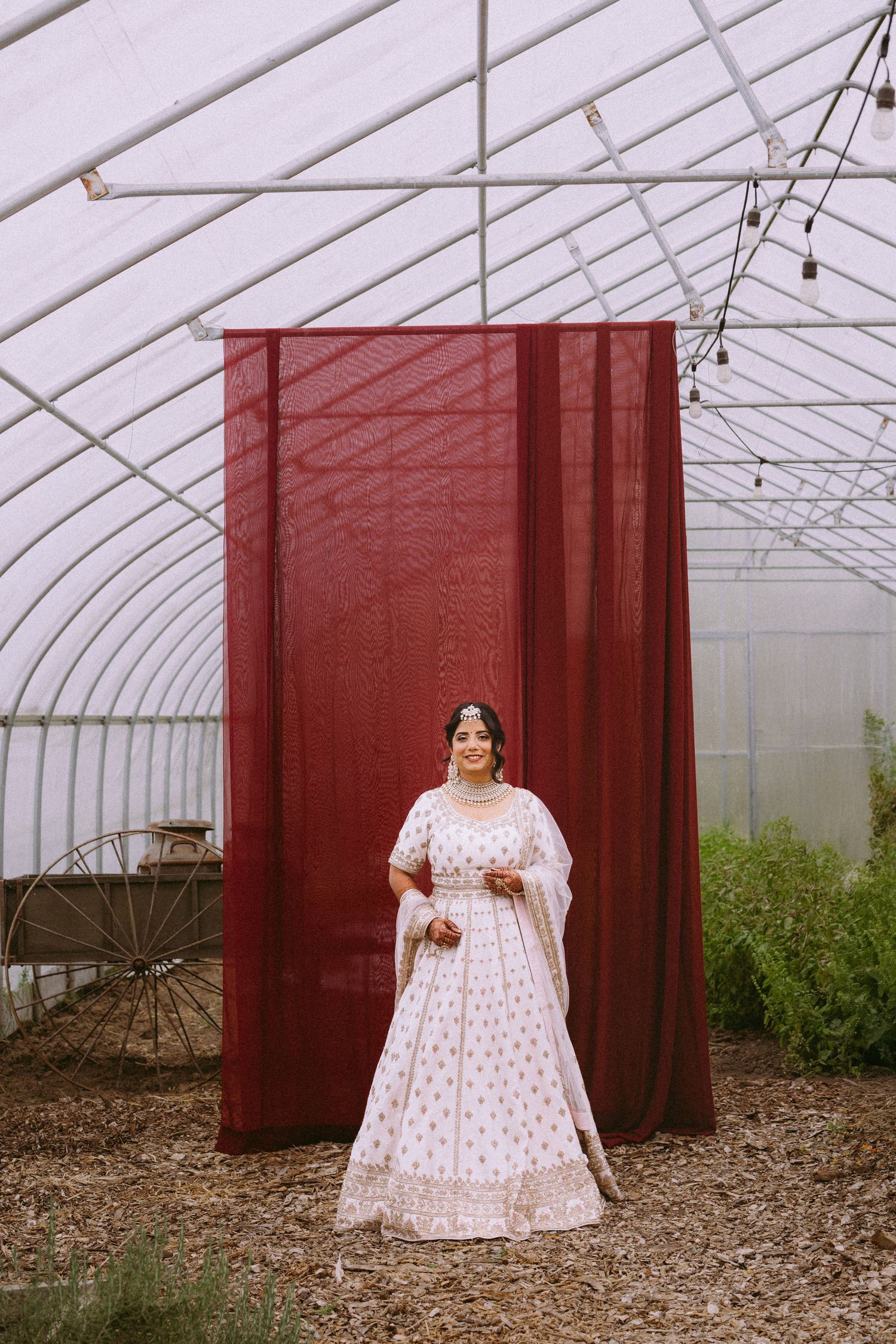White empire waist dress photographed in sequence inside a greenhouse with red curtains.