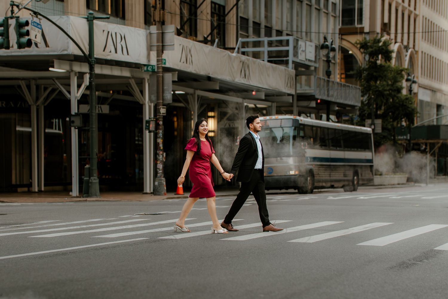 Urban street scene with pedestrians walking along storefronts and parked cars on a cloudy day.
