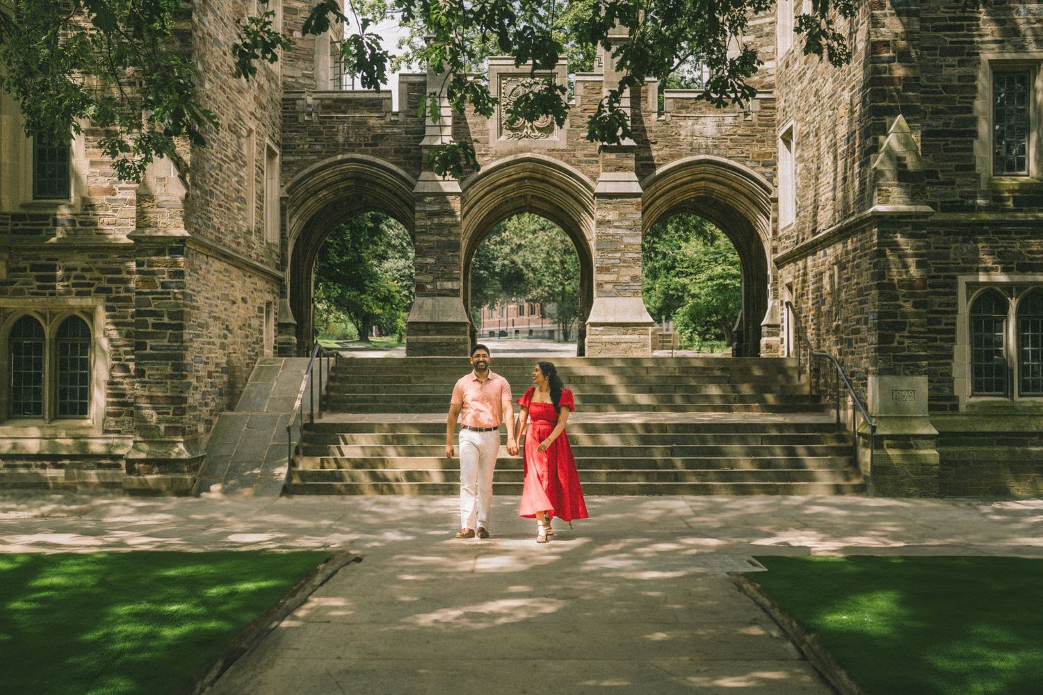 A panoramic view of a historic stone church exterior with Gothic architecture and lush green trees in summer.