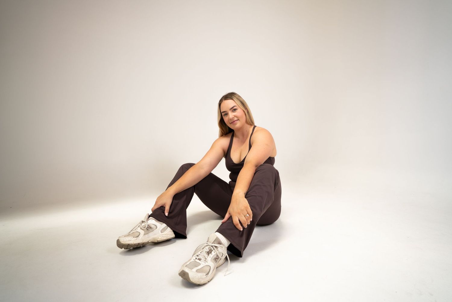 A person in a black outfit and white sneakers poses against a white backdrop in various reclining positions.