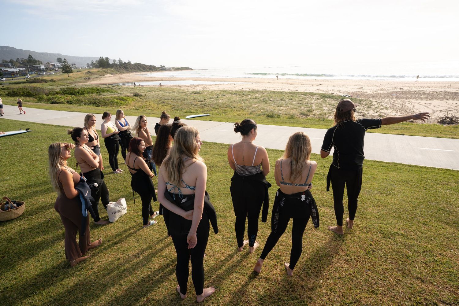Group walking along coastal path with ocean views at sunset.