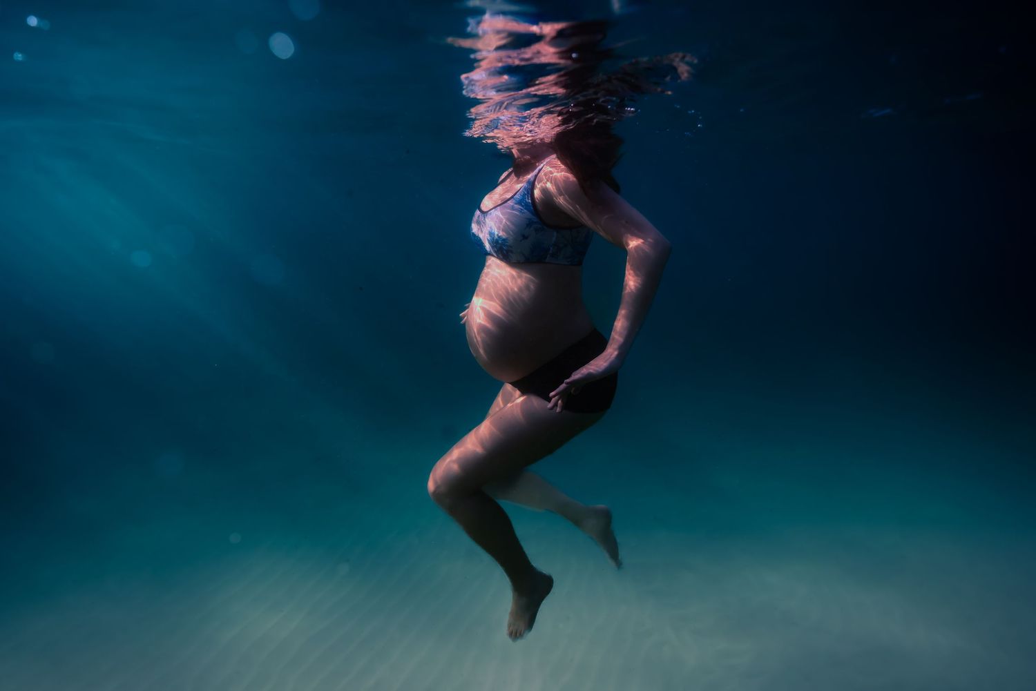 Underwater sequence showing someone floating and diving in deep blue water.