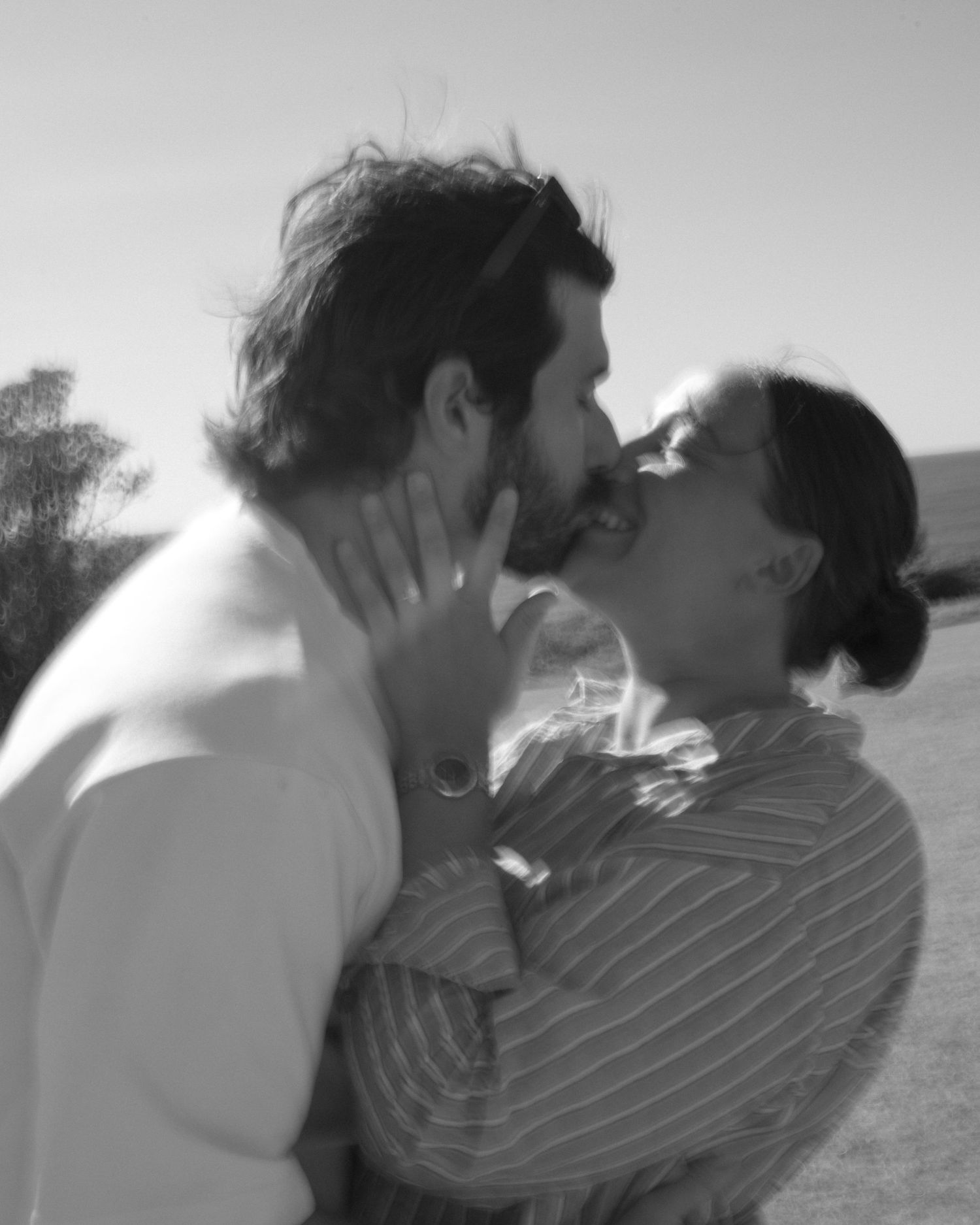 A black and white photo sequence showing two people in a progressive kissing motion outdoors.