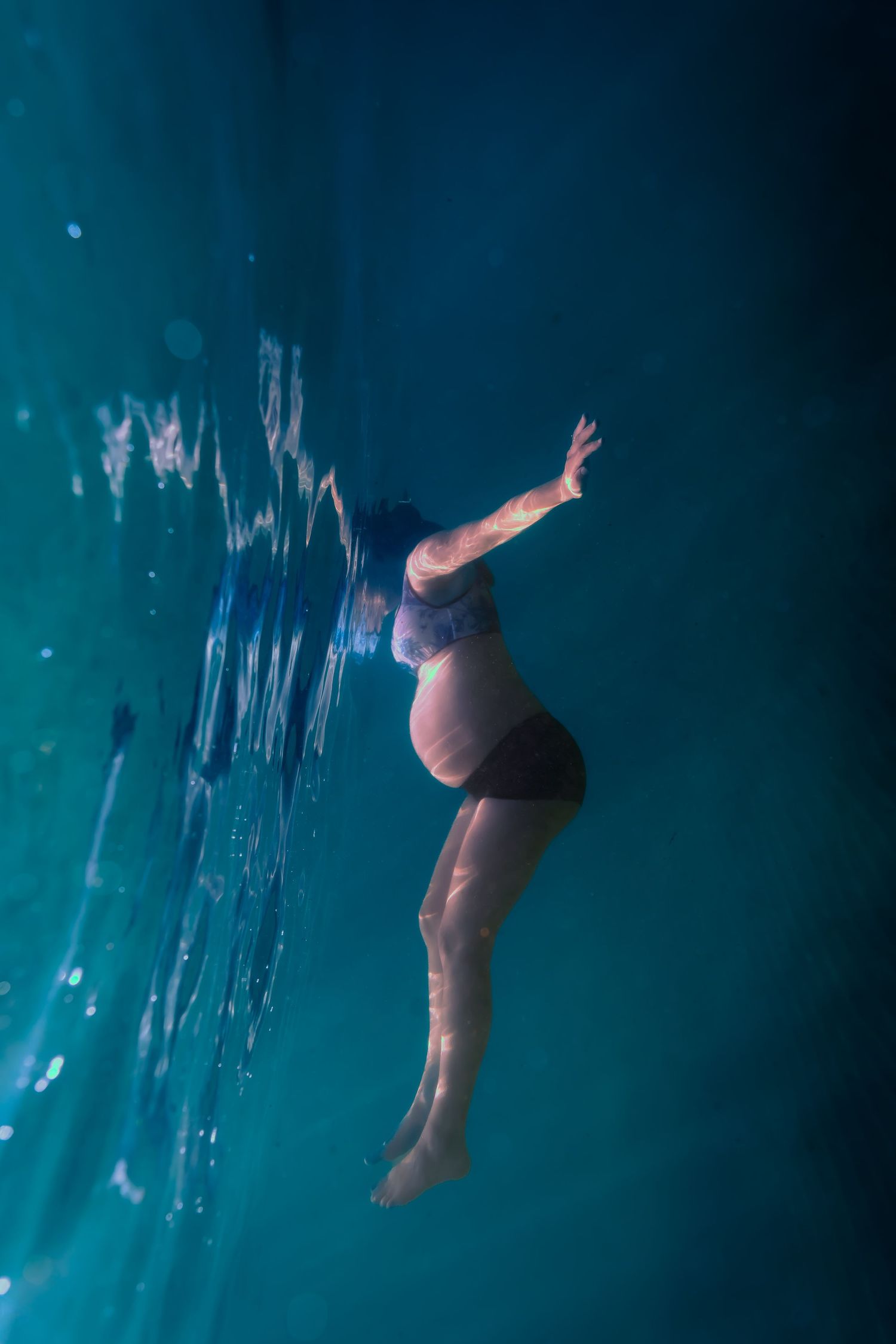 A sequence of underwater diving figures silhouetted against a deep turquoise blue background showing graceful movements.