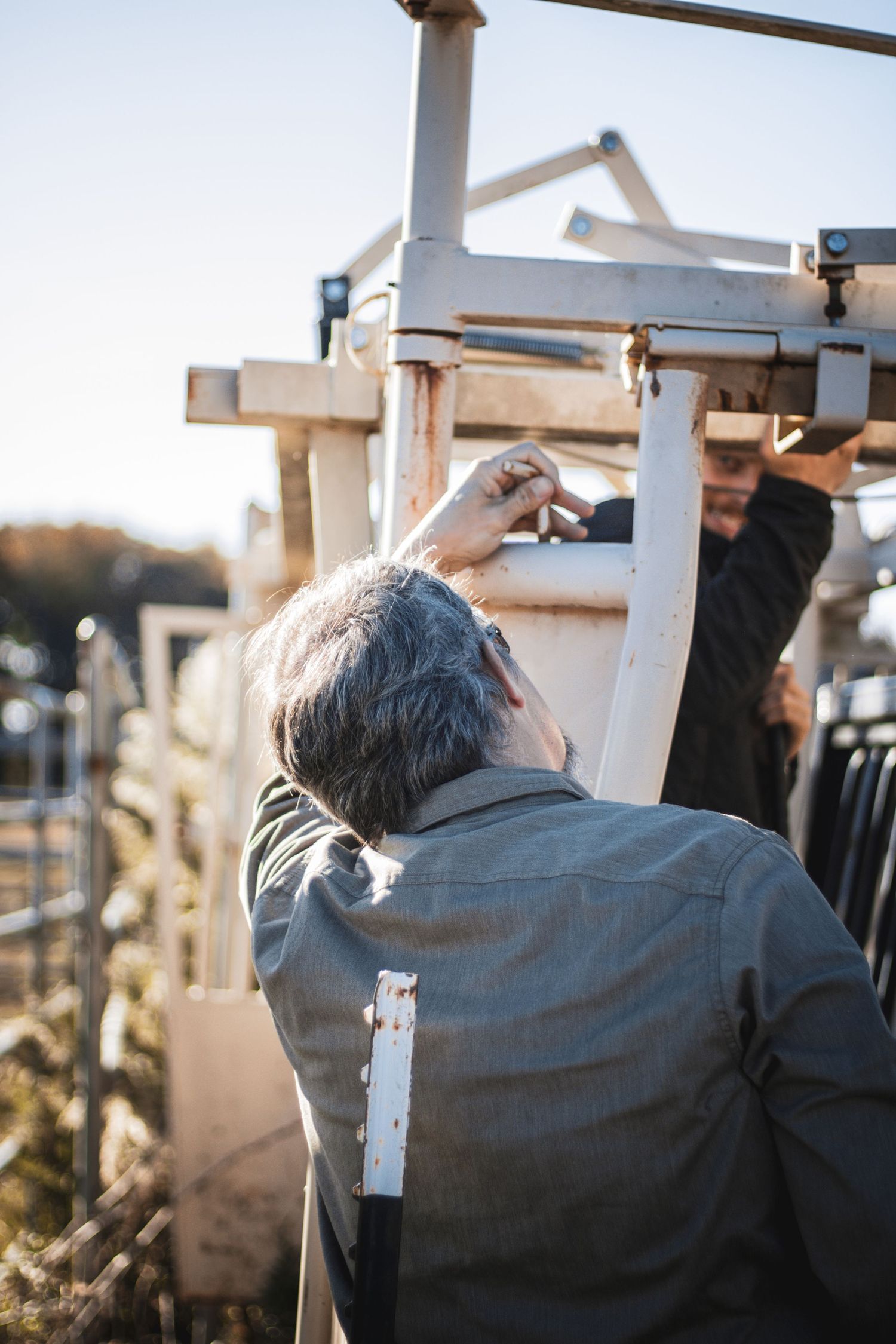 Person in gray jacket working on outdoor construction or repair project during golden hour lighting.