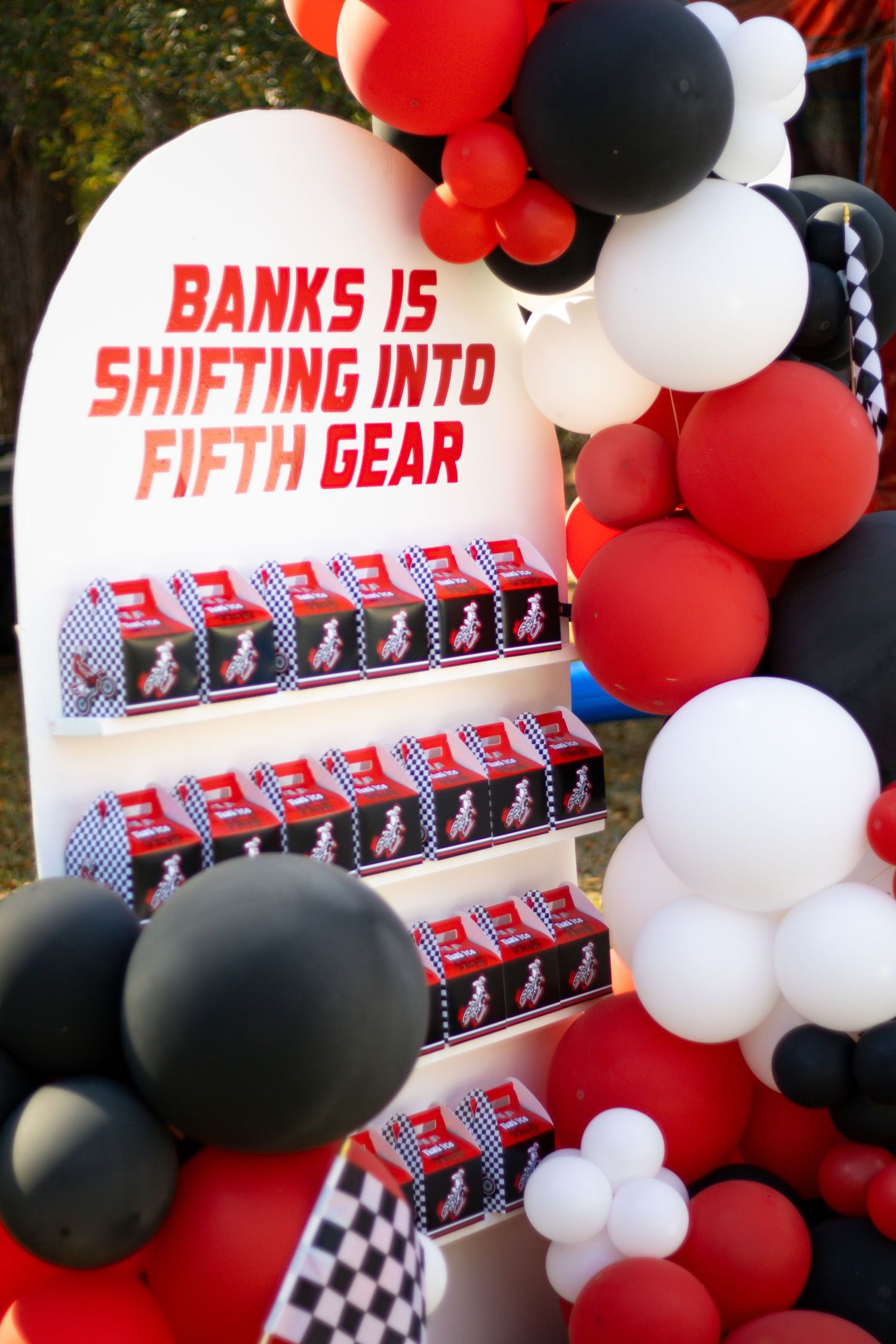 Racing-themed party decorations with red, black and white balloons and photo display.