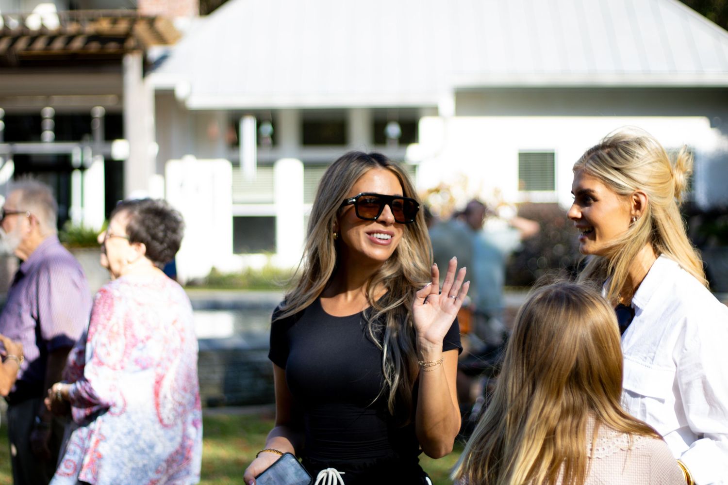 Group of people gathered outdoors at a social event on a sunny day.