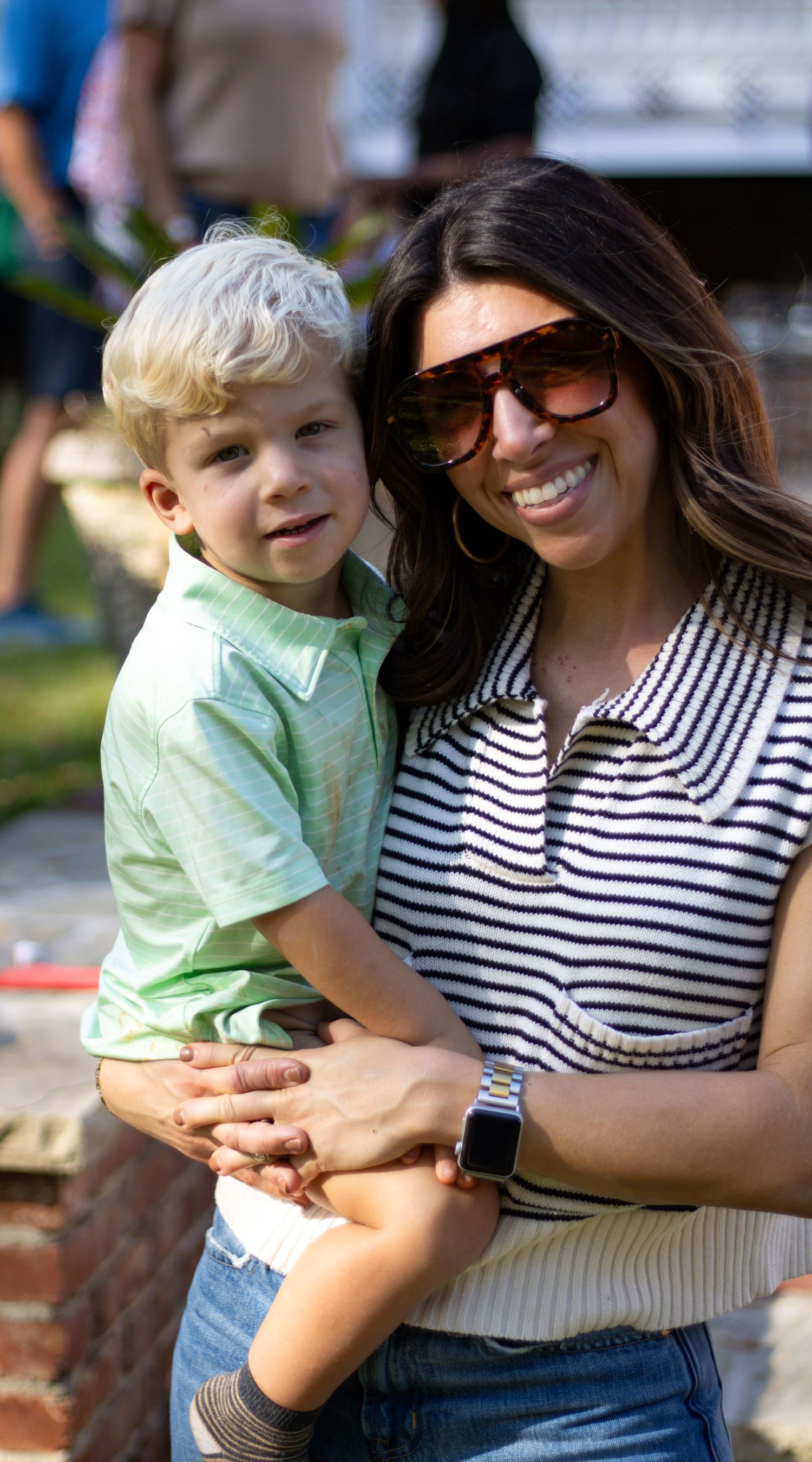 Parent and child in casual striped shirt enjoying a sunny day together.