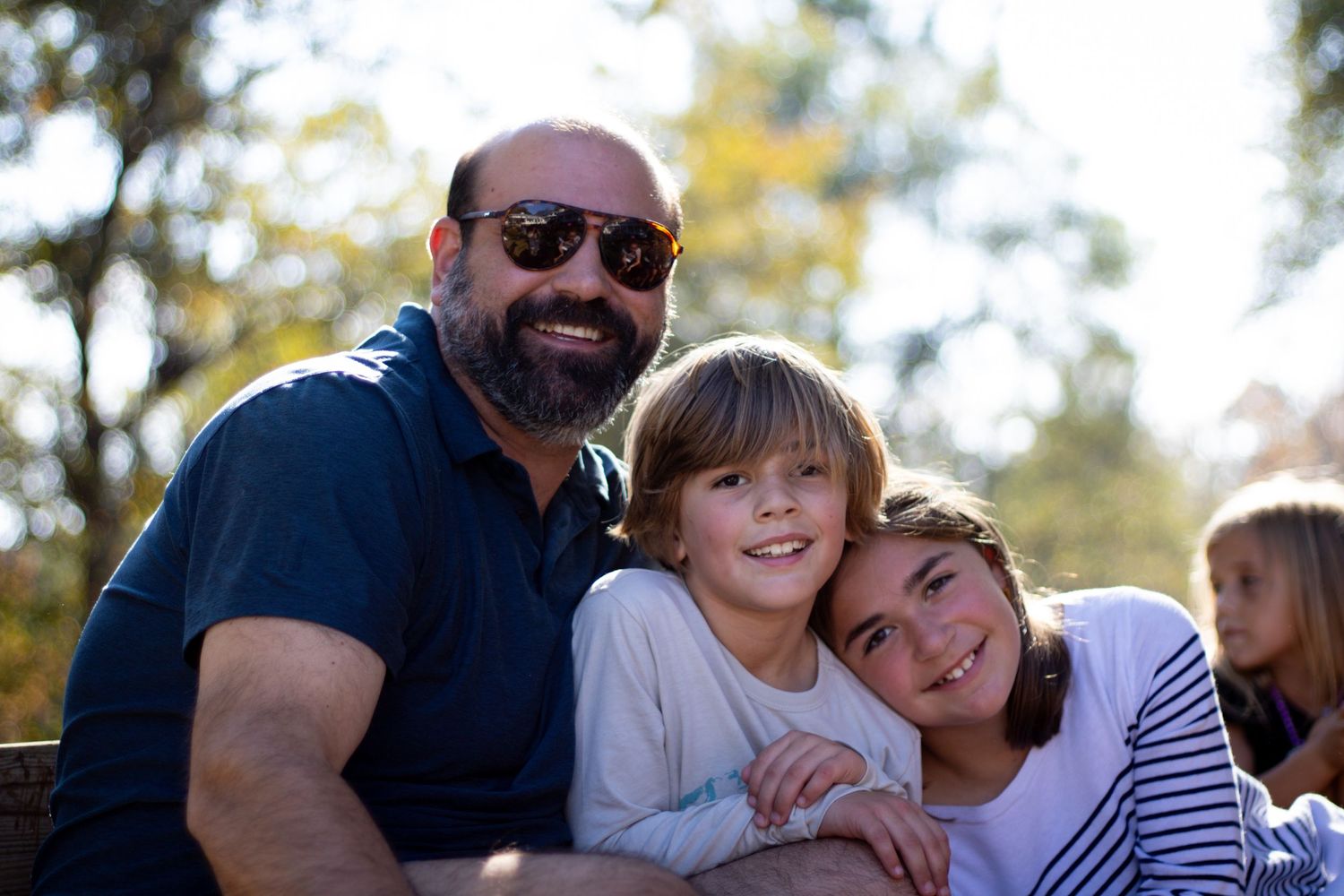 Family members sharing a warm embrace outdoors on a fall day.