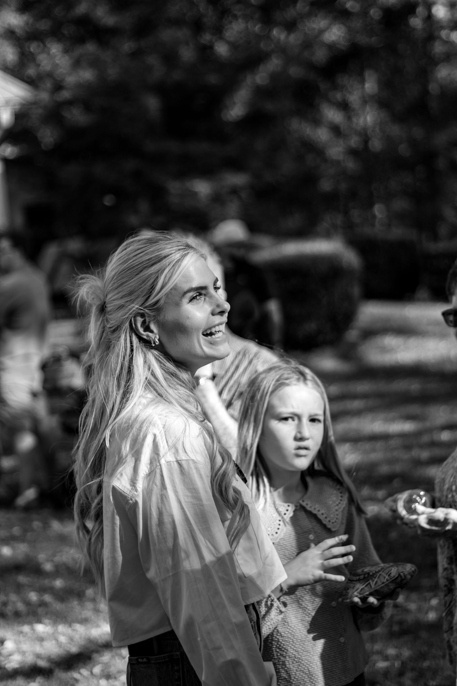 Two children in vintage-style clothing play outdoors in a black and white photograph.