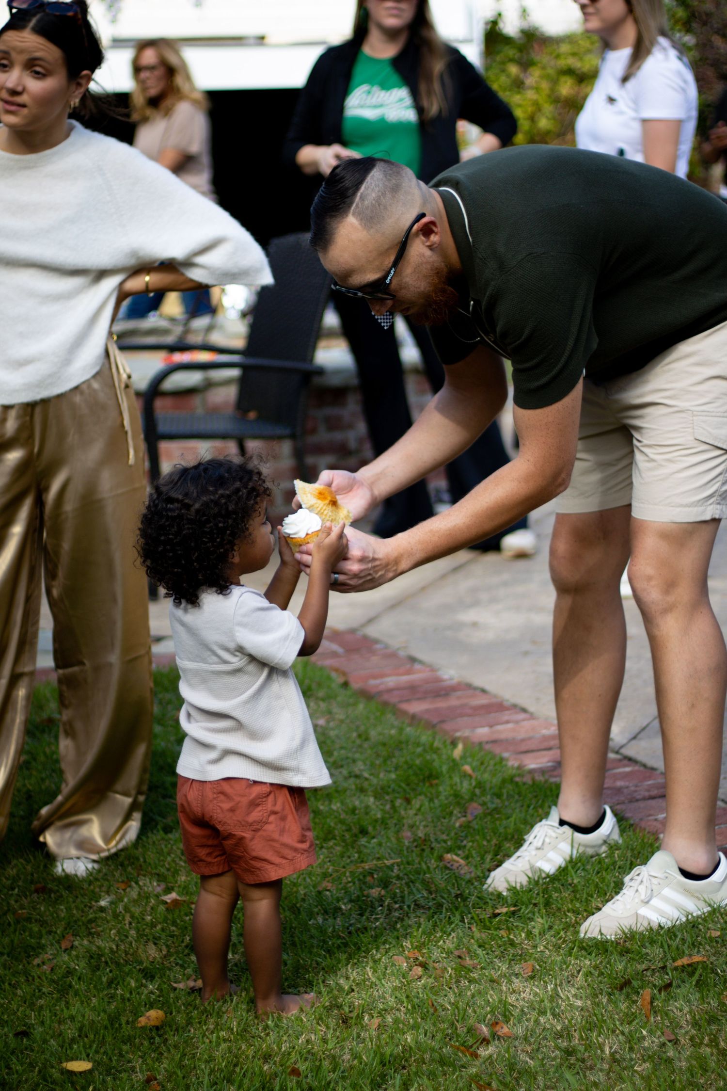 Low angle view of people's legs and feet on grass during an outdoor gathering.