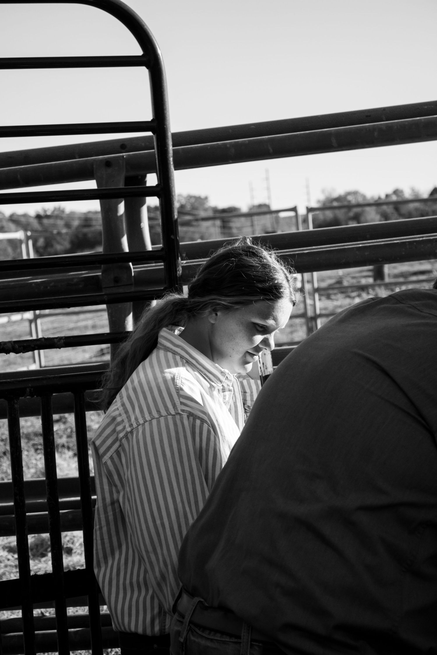 Black and white photograph showing two people sitting on a balcony or deck with railings visible in silhouette.