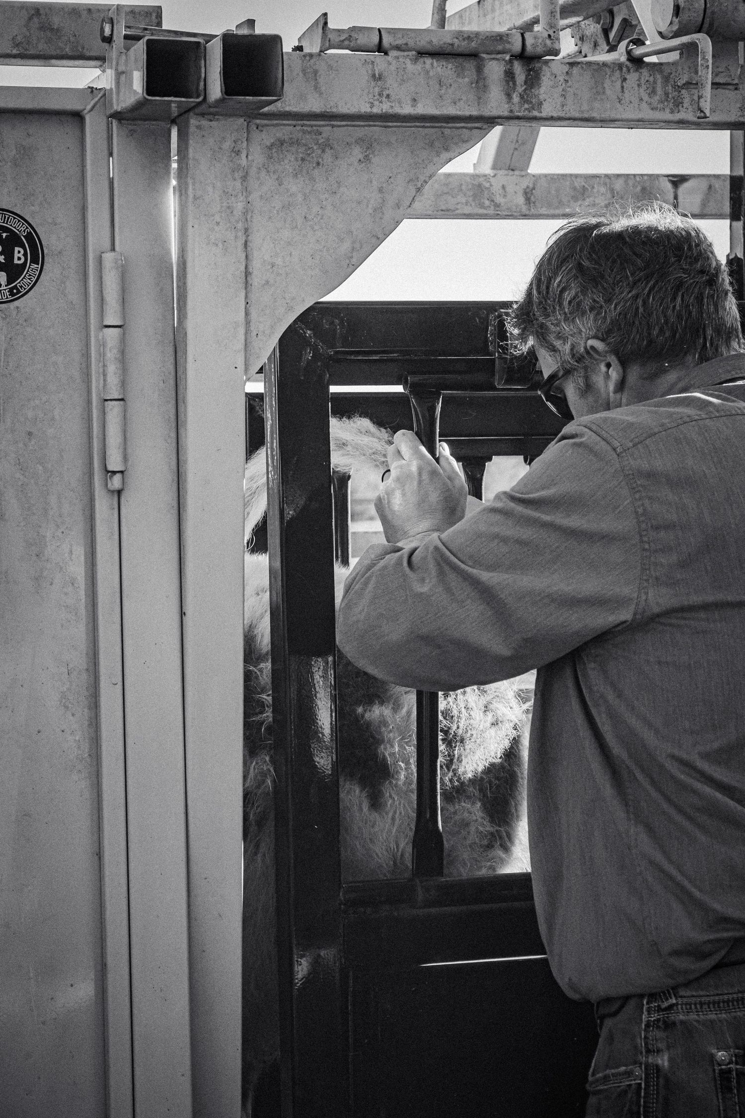 A person works on mechanical equipment in black and white photography.