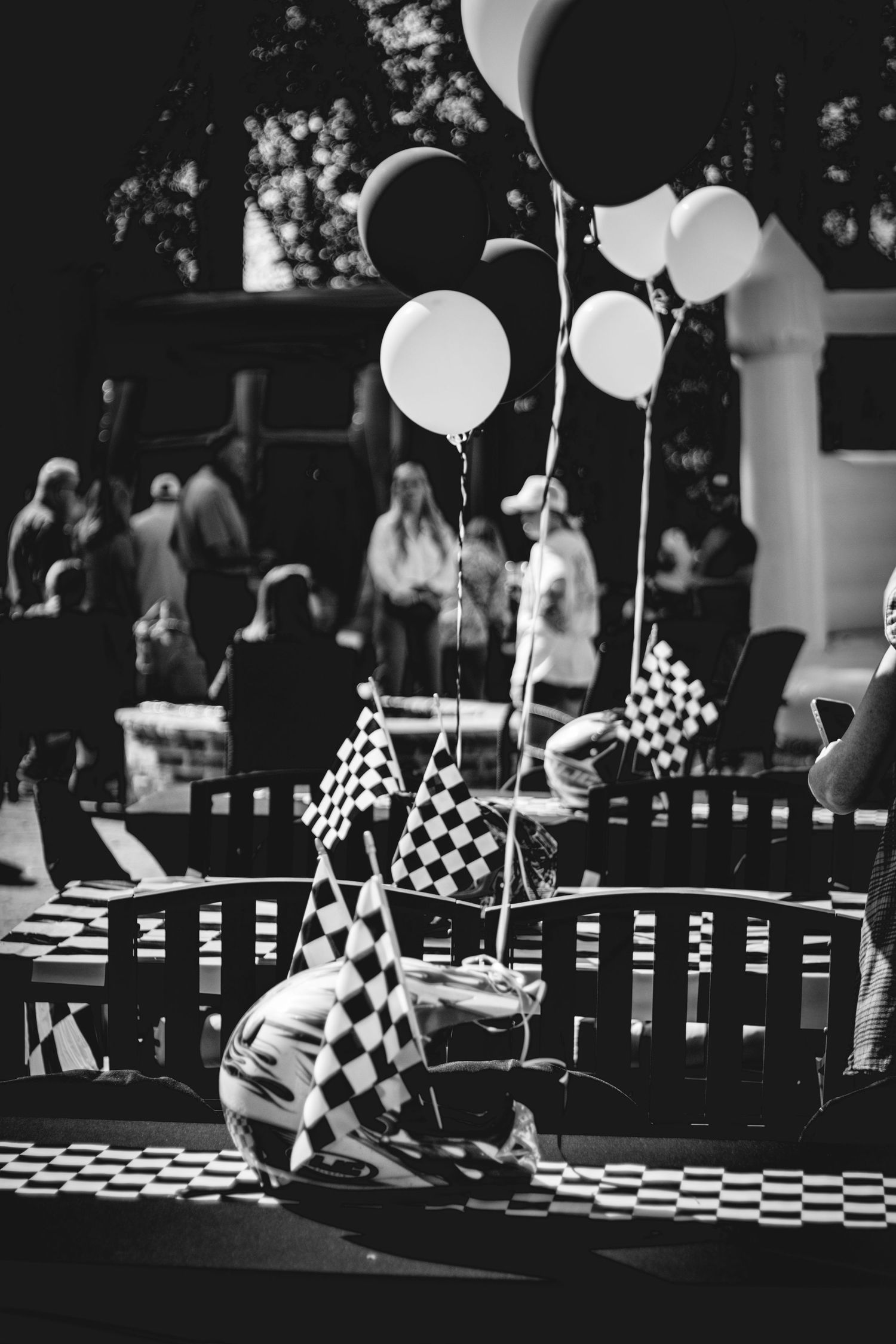 Black and white photo of a racing-themed party setup with checkered flags and balloons.
