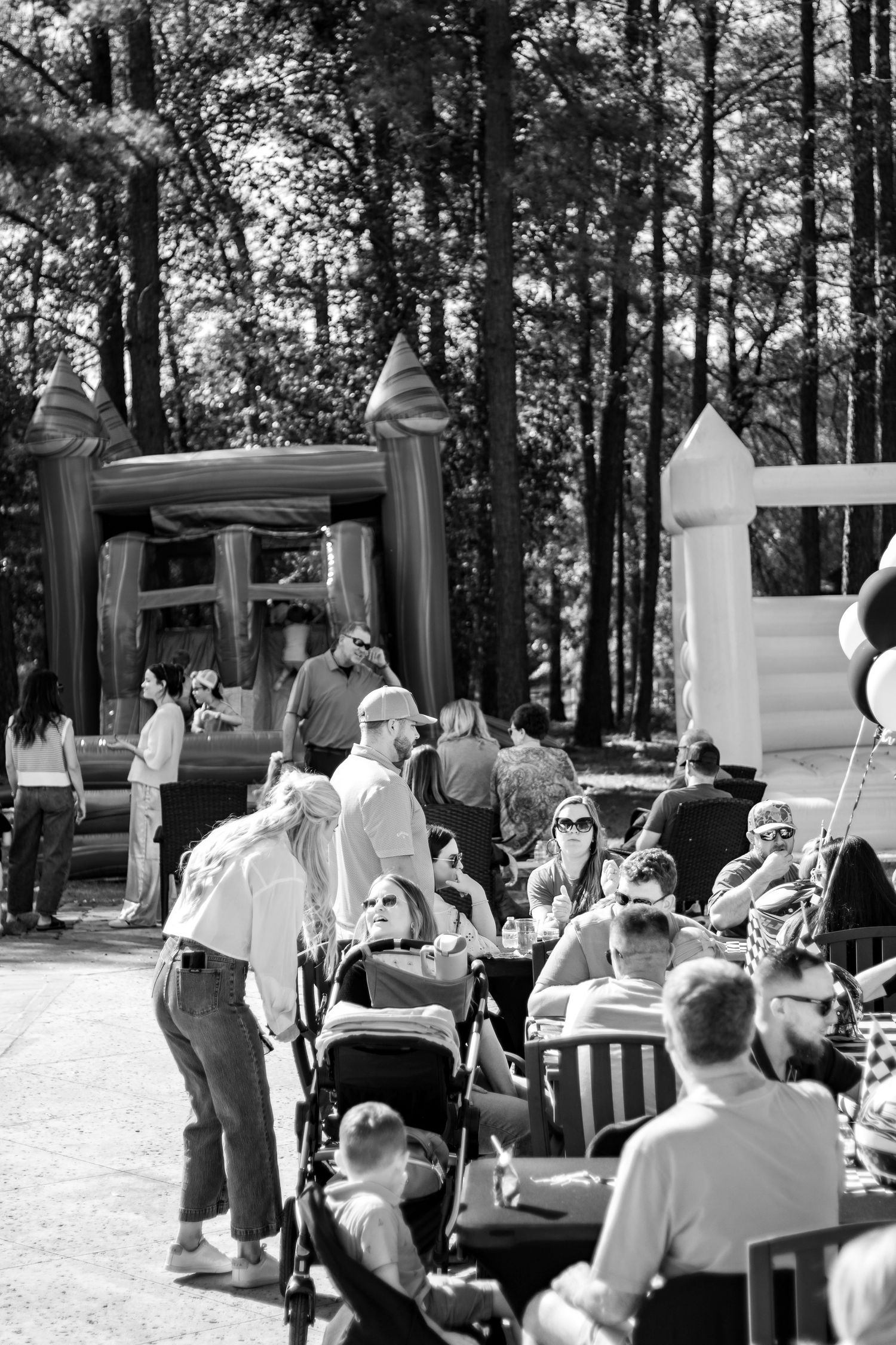 An outdoor party setup with inflatable decorations and people gathering in a wooded area.
