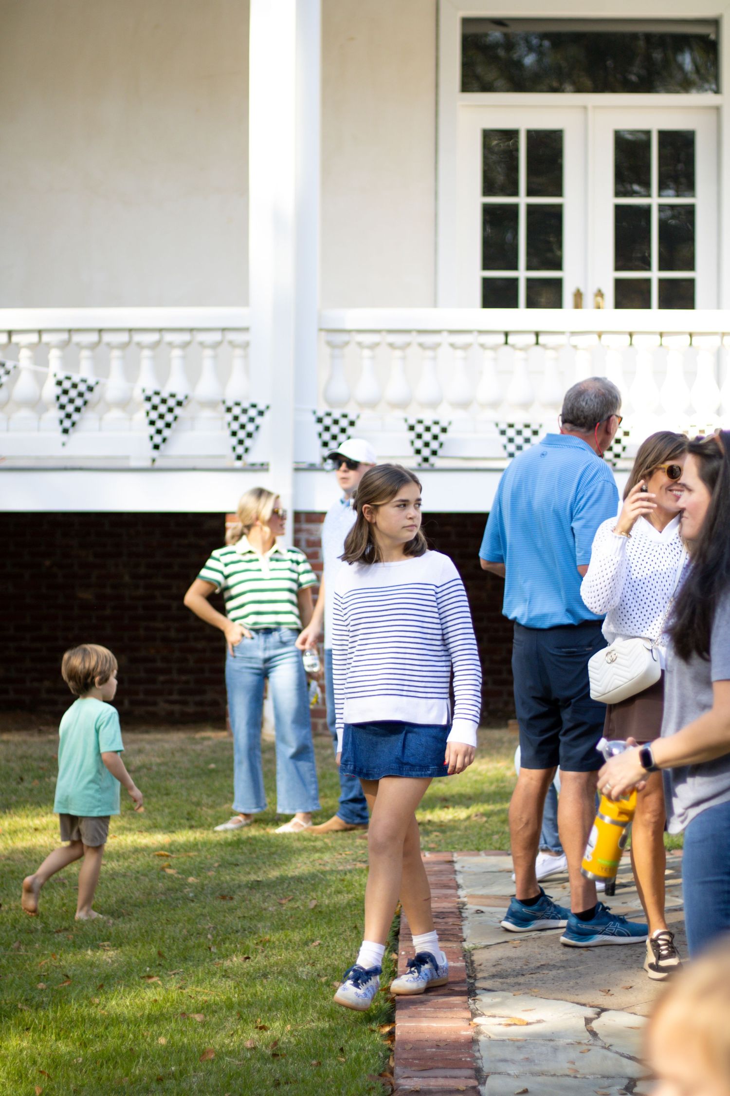 Group of people socializing outside a white building with checkered flag decorations.