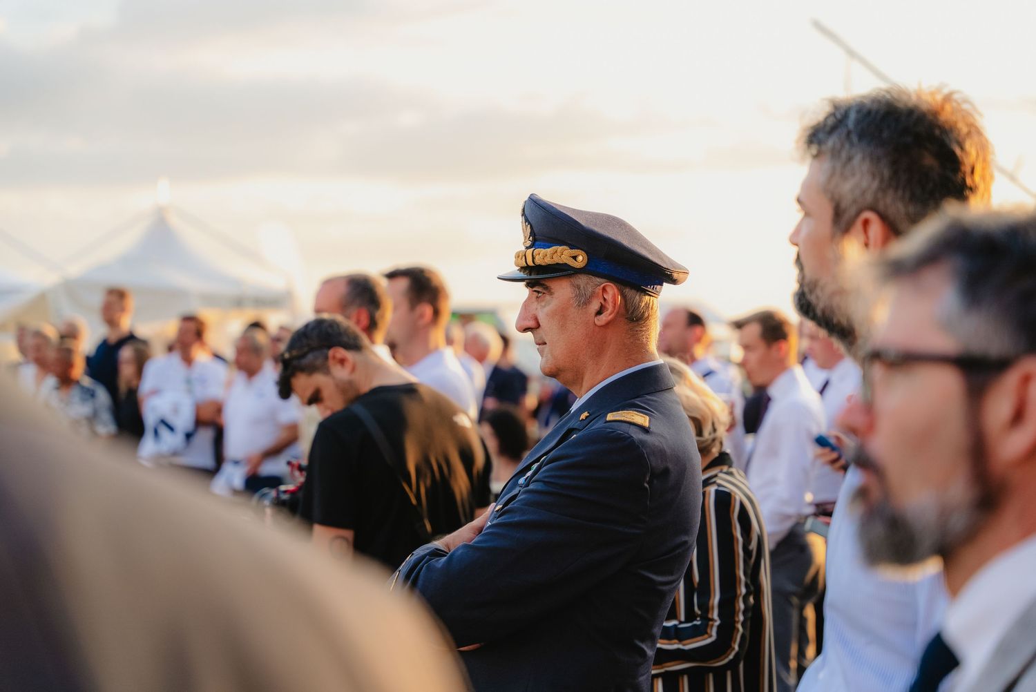 A series of candid moments from a naval ceremony with officers in white uniforms against a bright sky.