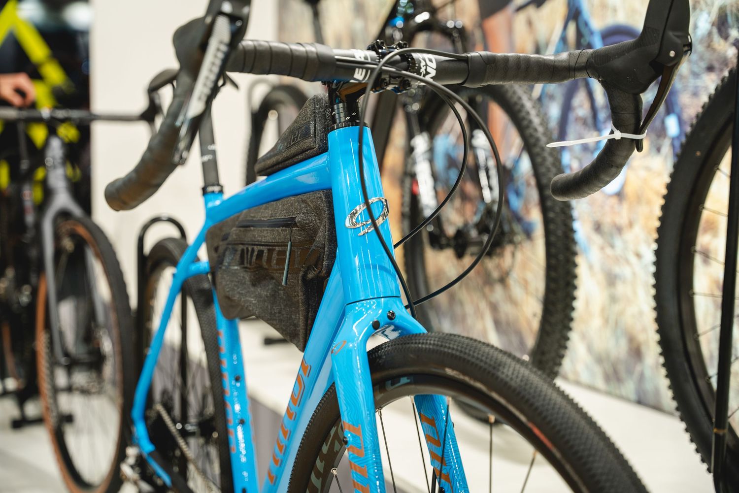 Close-up view of bicycle frames and parts displayed in a retail bike shop setting with bright blue bikes visible.