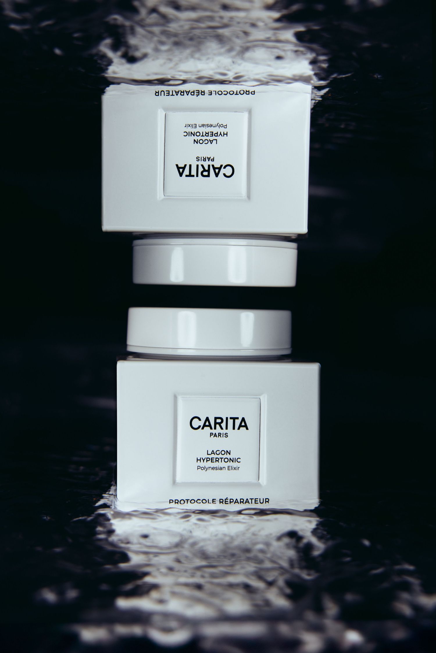 Stacked white luxury skincare jars from Carita beauty brand against dark background.