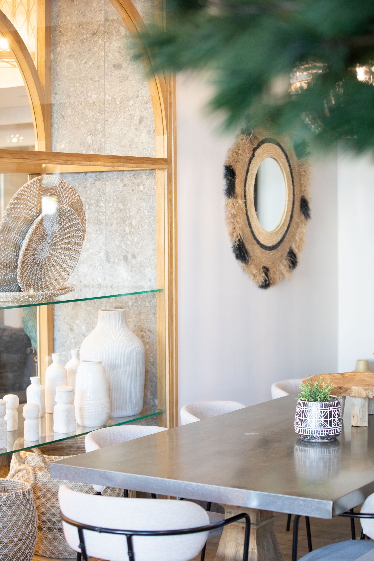 Elegant dining room interior with gold-framed sunburst mirrors, glass shelving, and white ceramic decor against neutral walls.