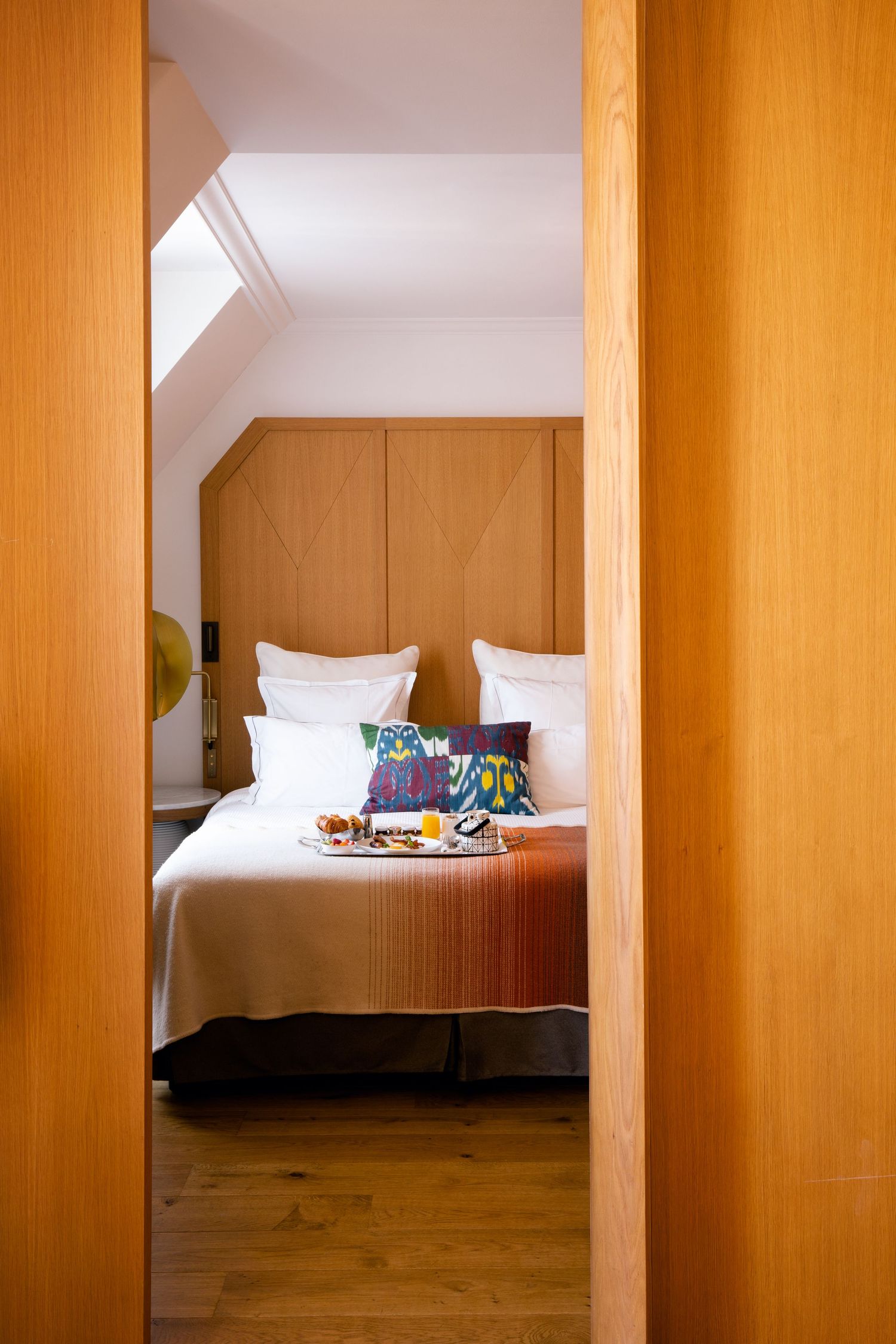 Modern bedroom interior with wooden partition walls and white bedding visible through vertical slats.