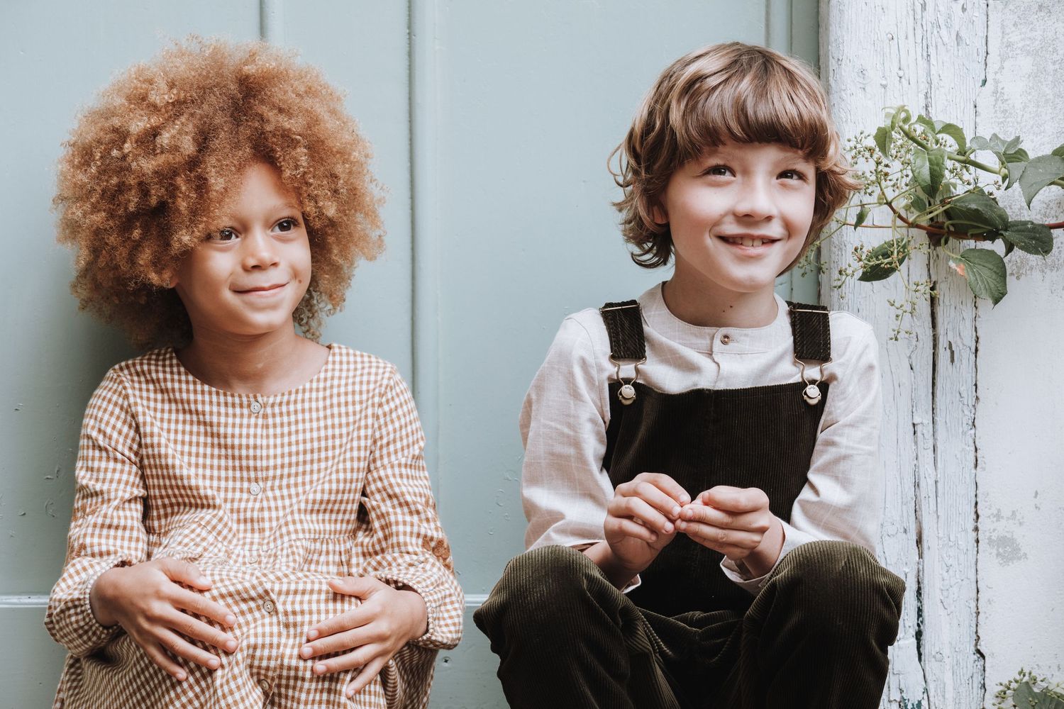 A series of connected photos showing a person with curly ginger hair in overalls and a checkered shirt by a white wall.