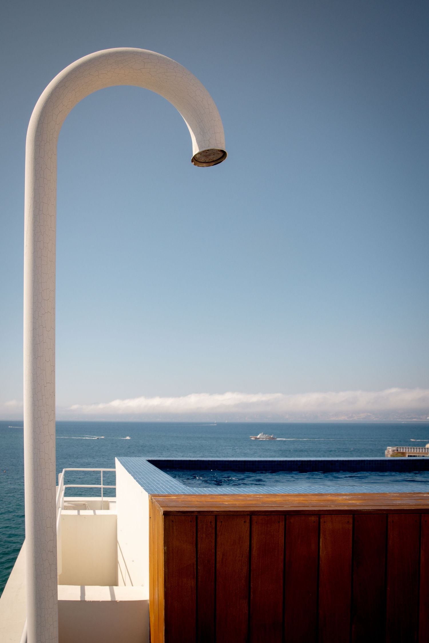 White arched columns frame a scenic Mediterranean seascape view with blue waters and clear skies.