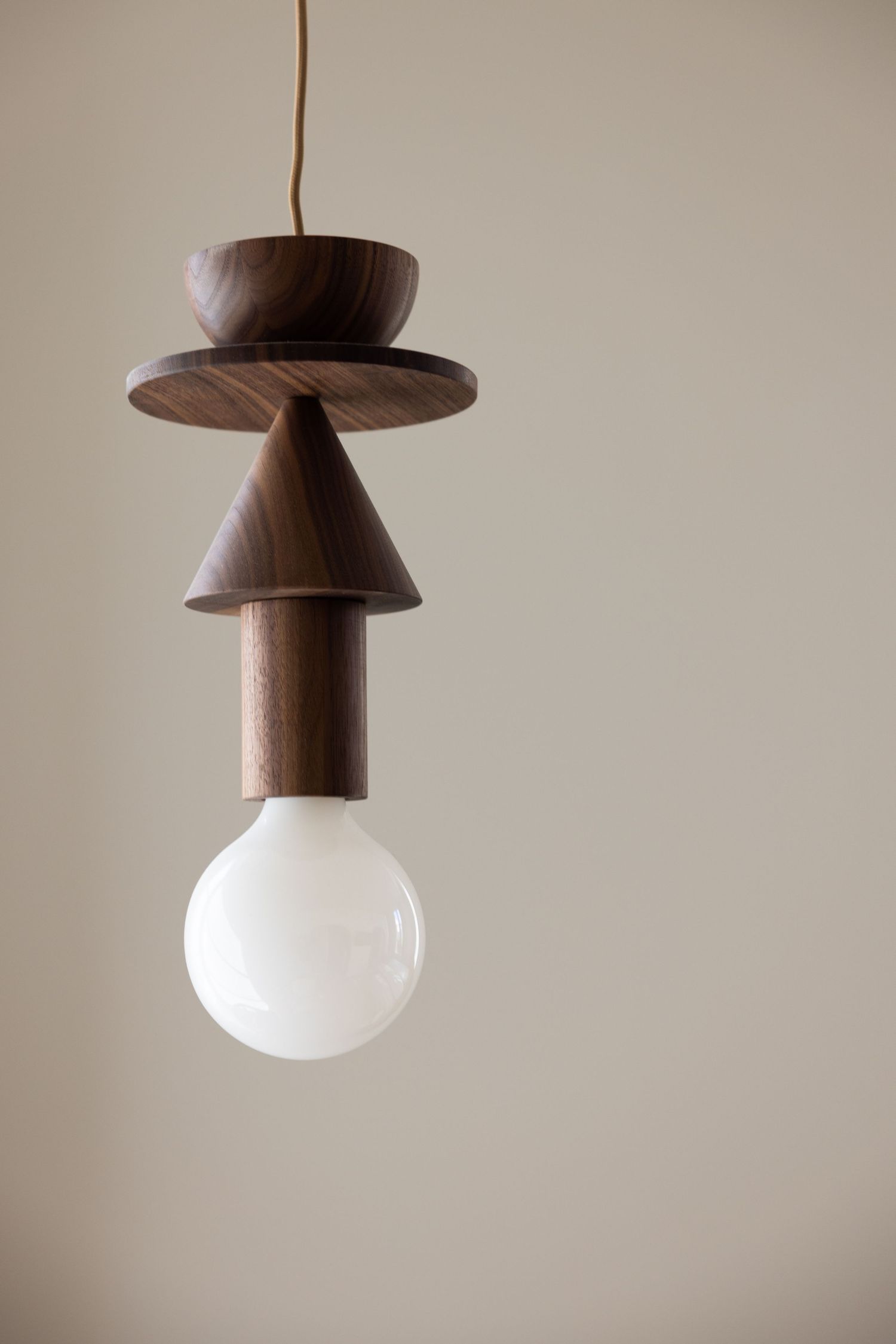 Minimalist wooden pendant light fixtures with frosted glass globes shown in a series against a neutral beige background.