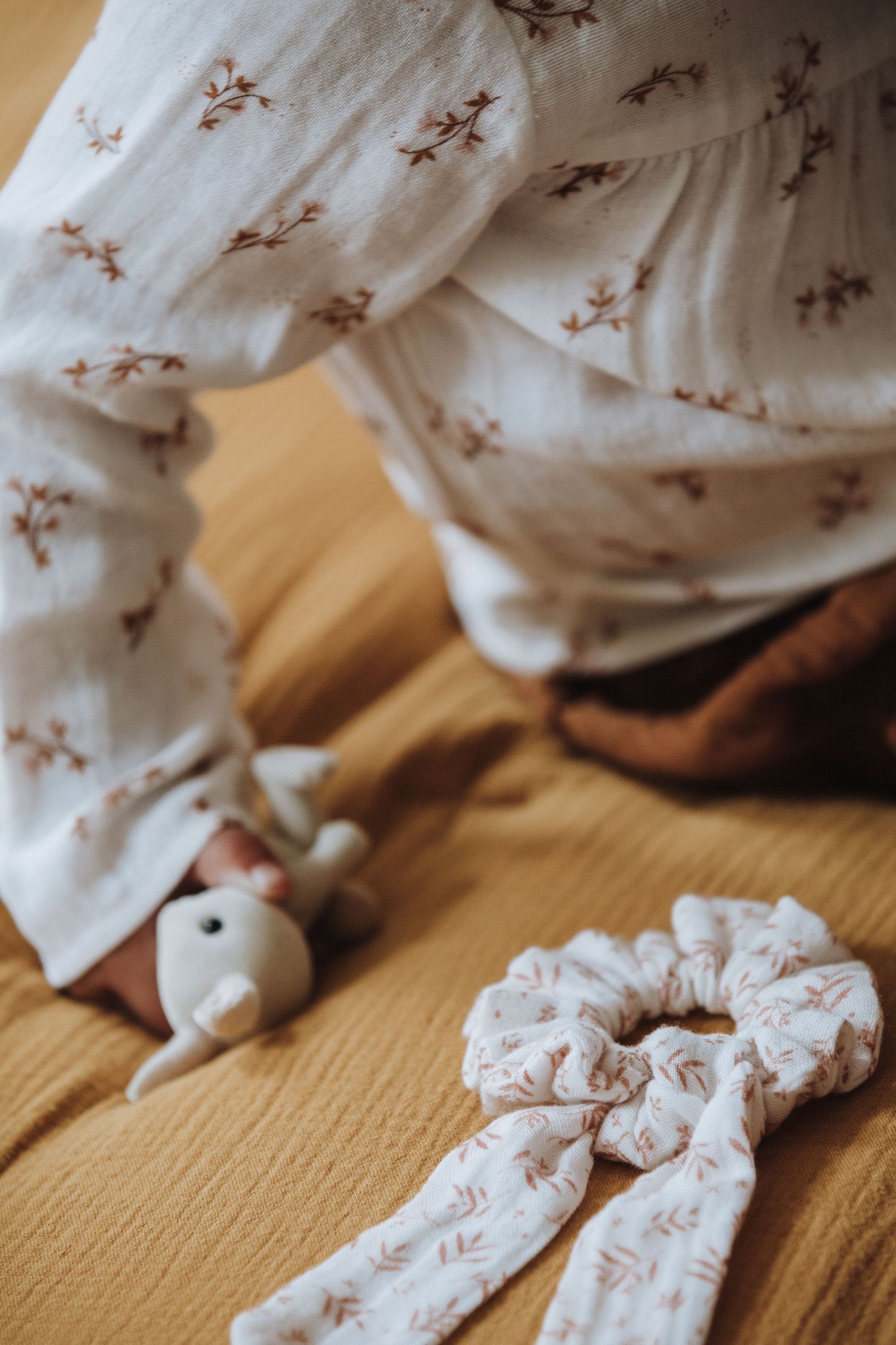 A series of white fabric pieces with delicate floral patterns arranged in sequence on a wooden surface.