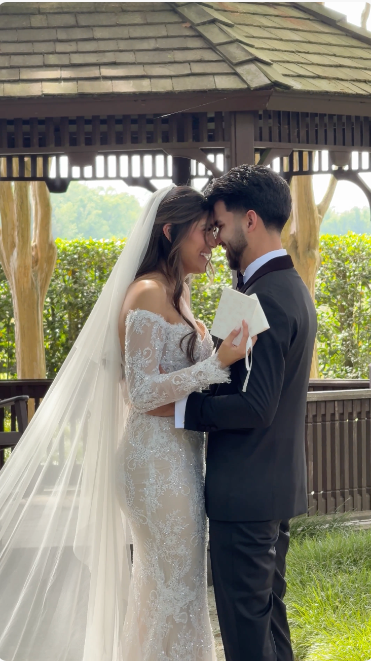 A bride and groom share an intimate moment under a gazebo, exchanging vows in a lush garden wedding ceremony.